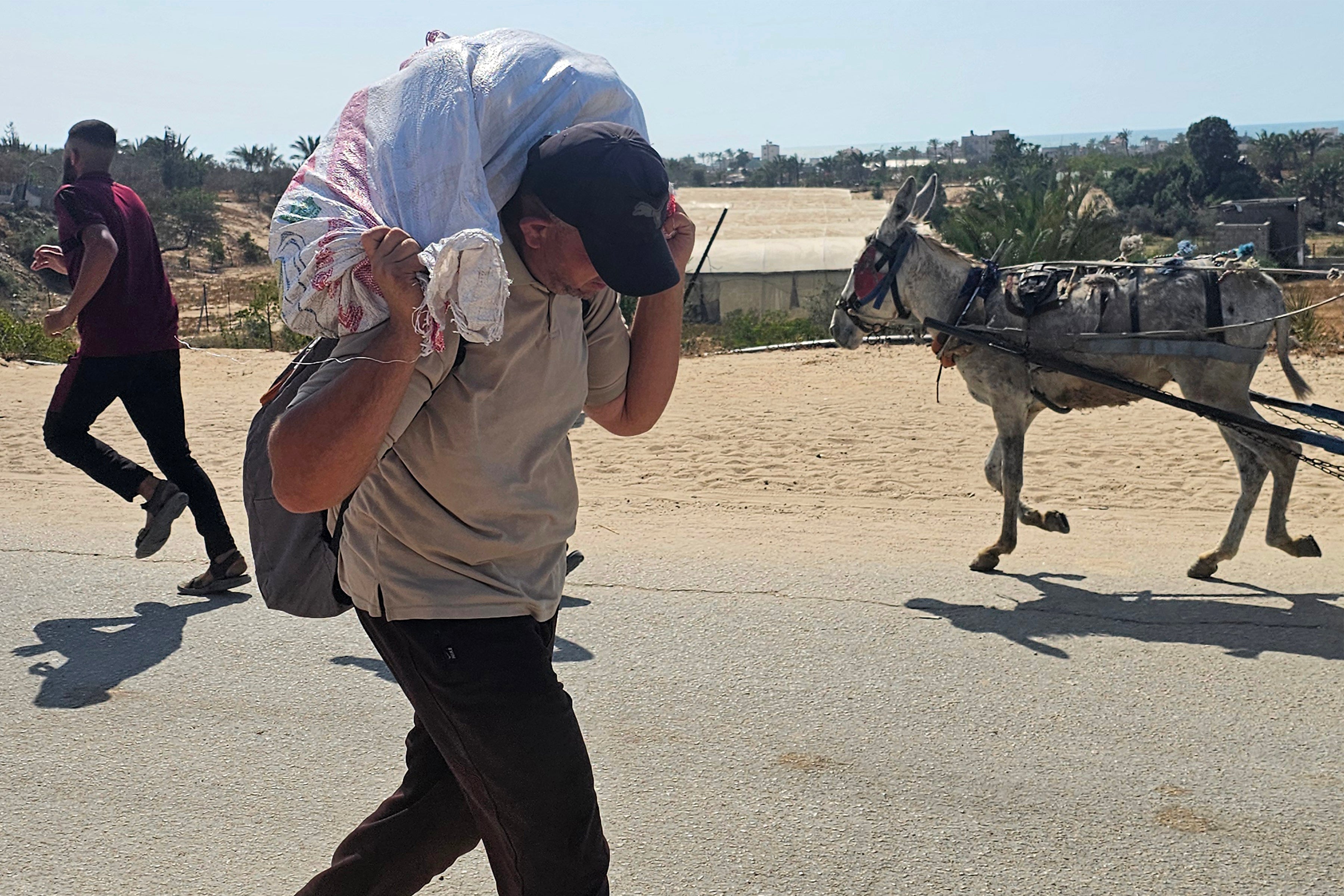 A man walks with a sack on his back as displaced Palestinians receive humanitarian aid in Rafah