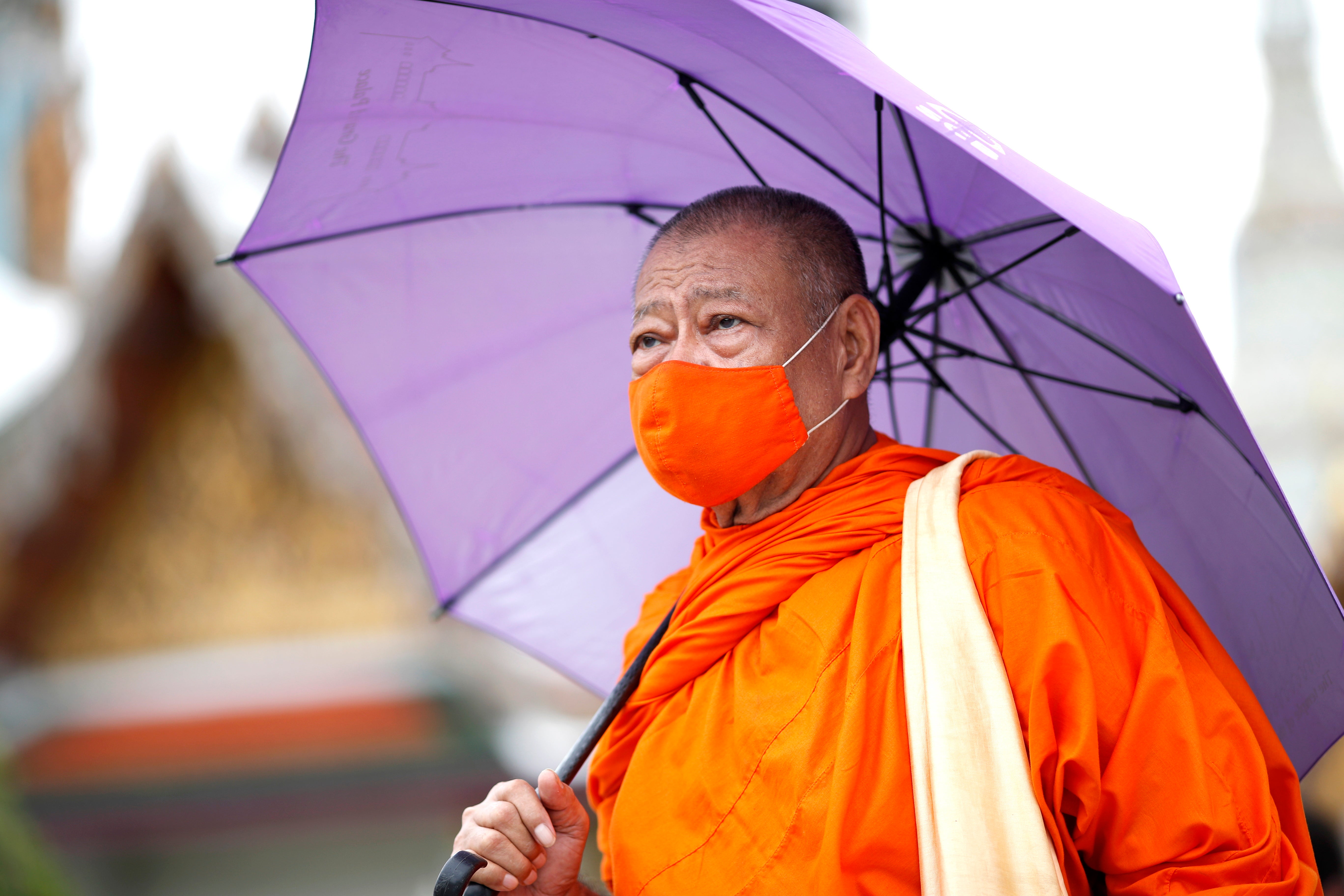 A monk wears a face mask at the Temple of the Emerald Buddha in Bangkok
