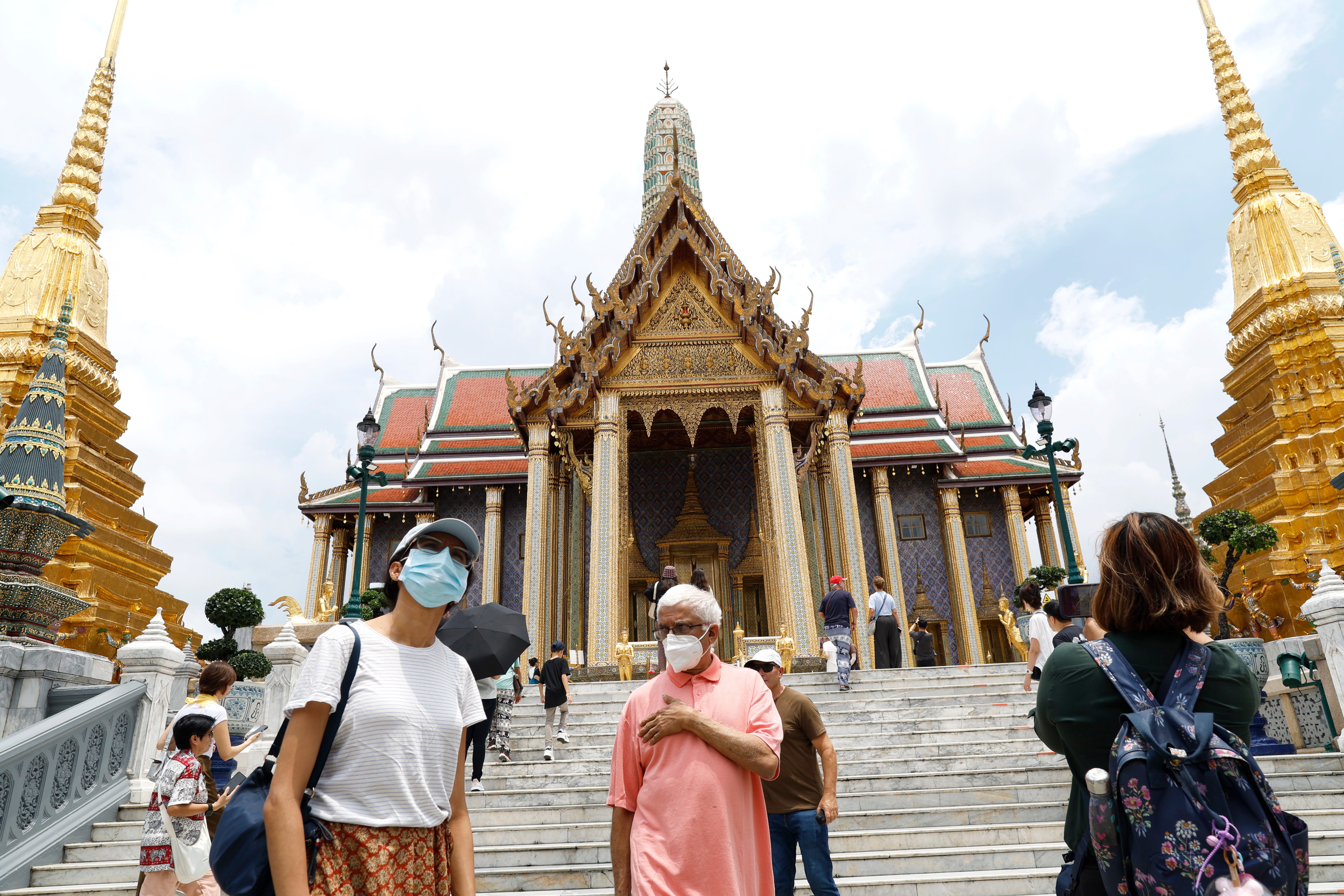 People wear face masks at the Temple of the Emerald Buddha in Bangkok, Thailand