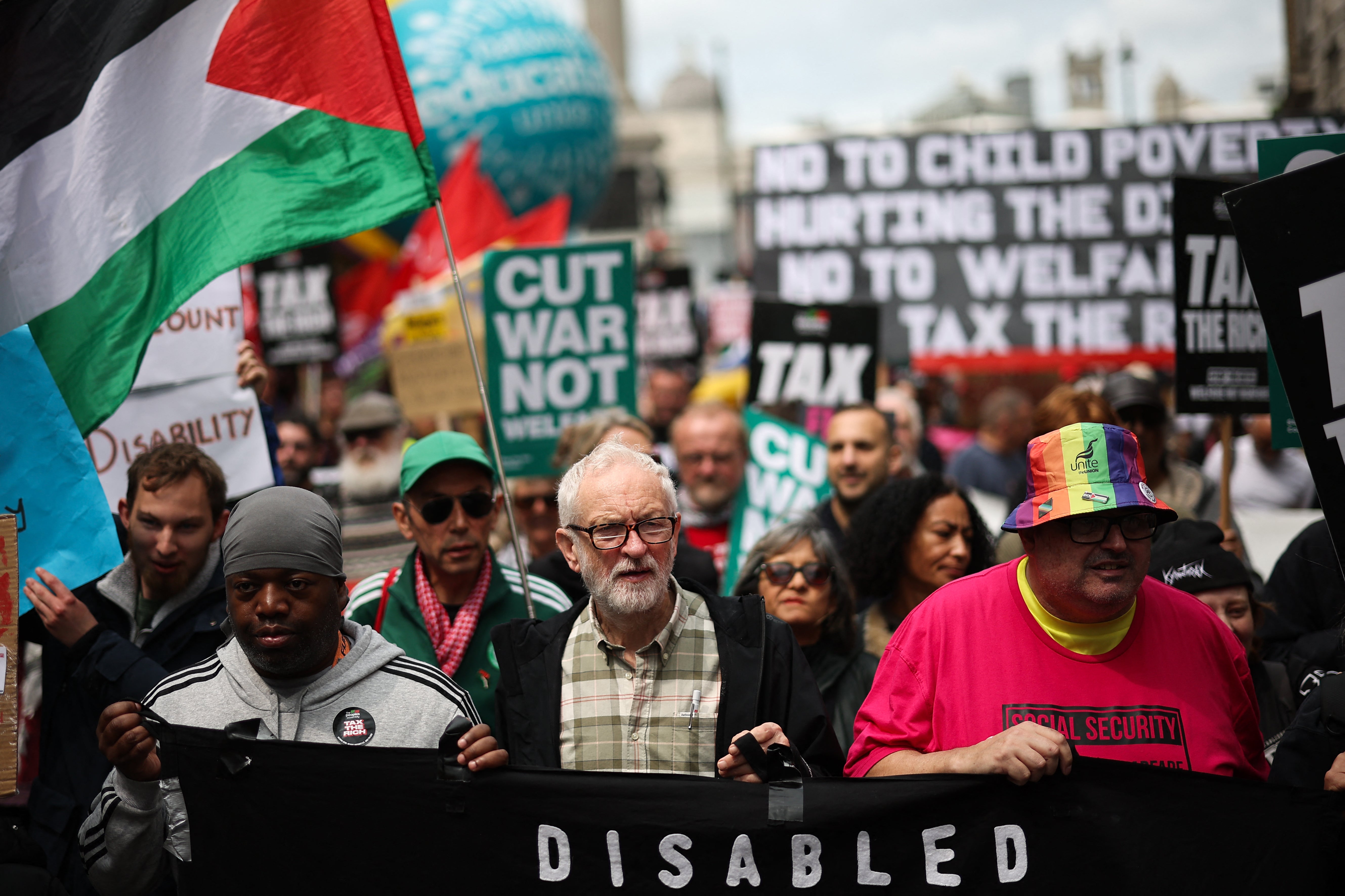 Independent MP Jeremy Corbyn (C) holds a banner as he takes part in the "No More Austerity 2.0" march in central London on June 7, 2025