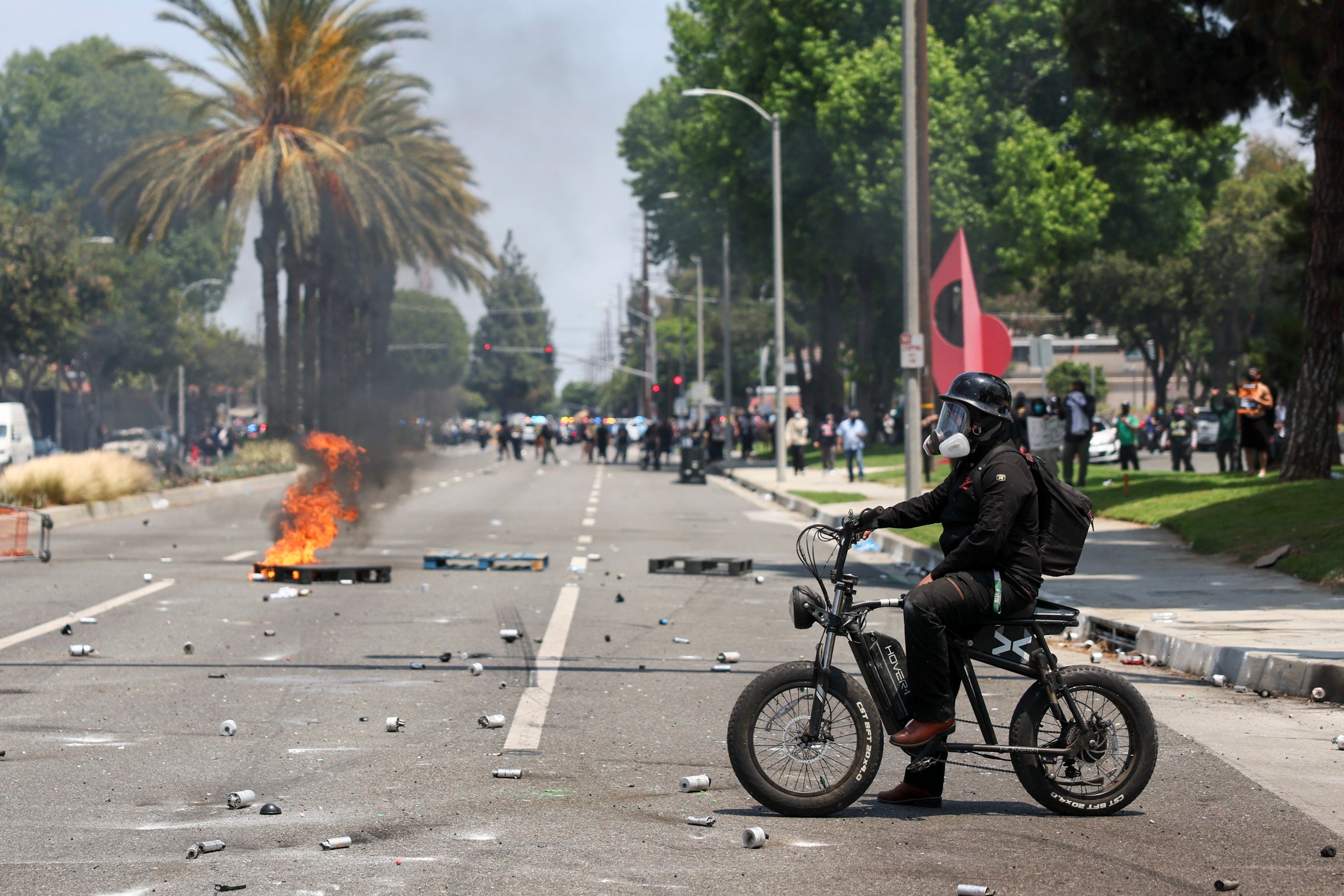 A protester sits on a bike as a crate burns in the street