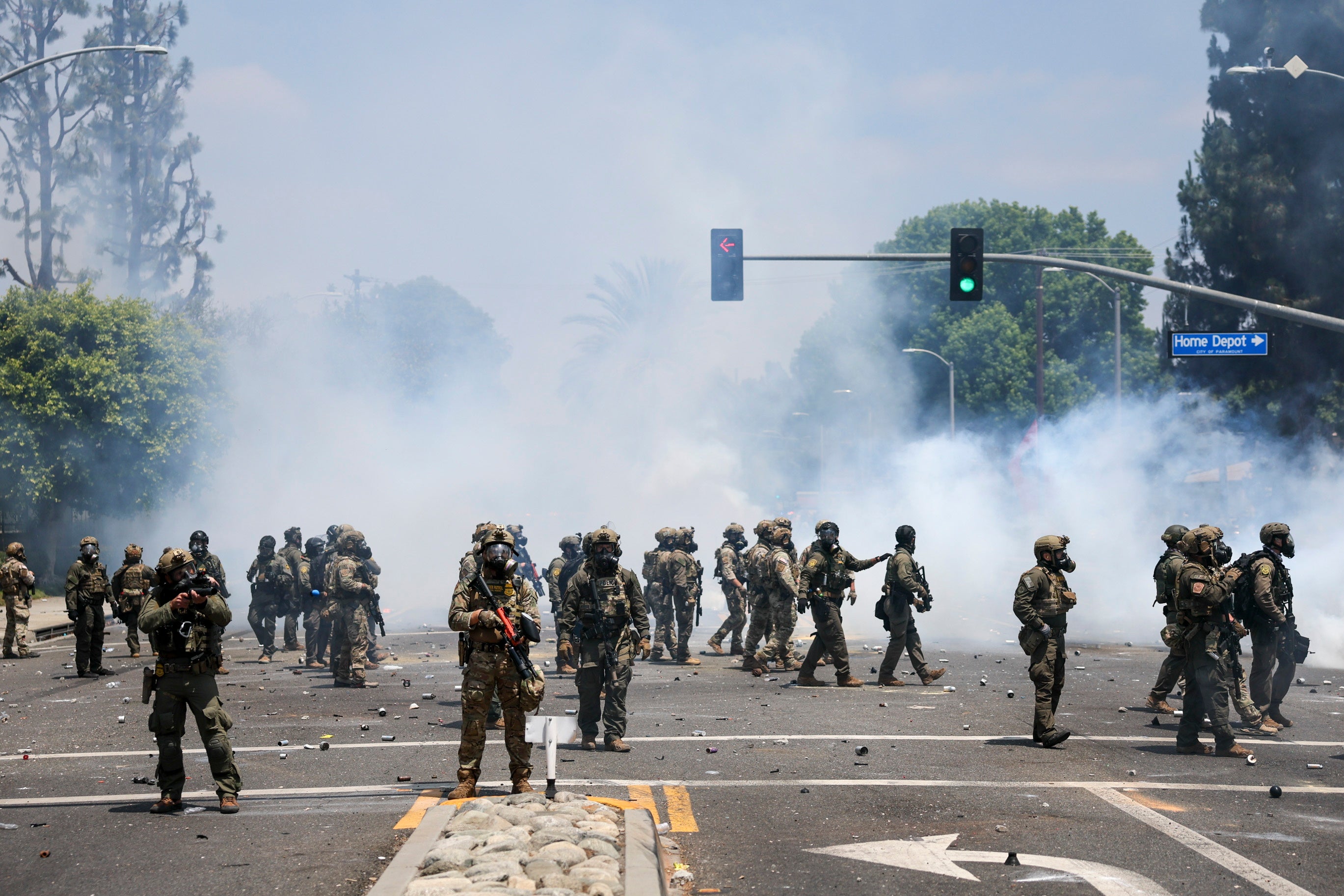 Armed law enforcement officers pictured against a backdrop of smoke