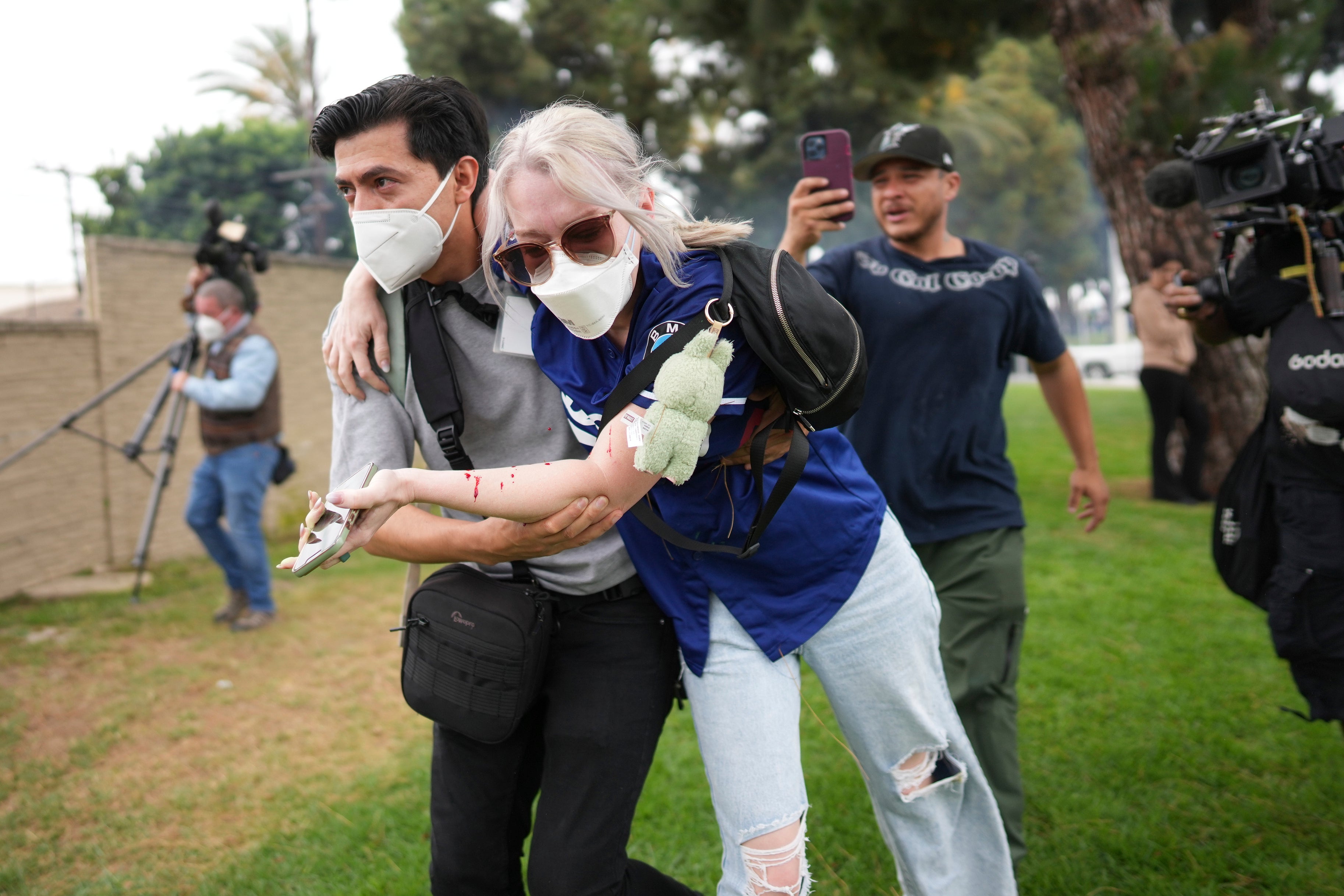 A man helps an injured woman during a protest in the Paramount section of Los Angeles, Saturday, June 7, 2025, after federal immigration authorities conducted operations