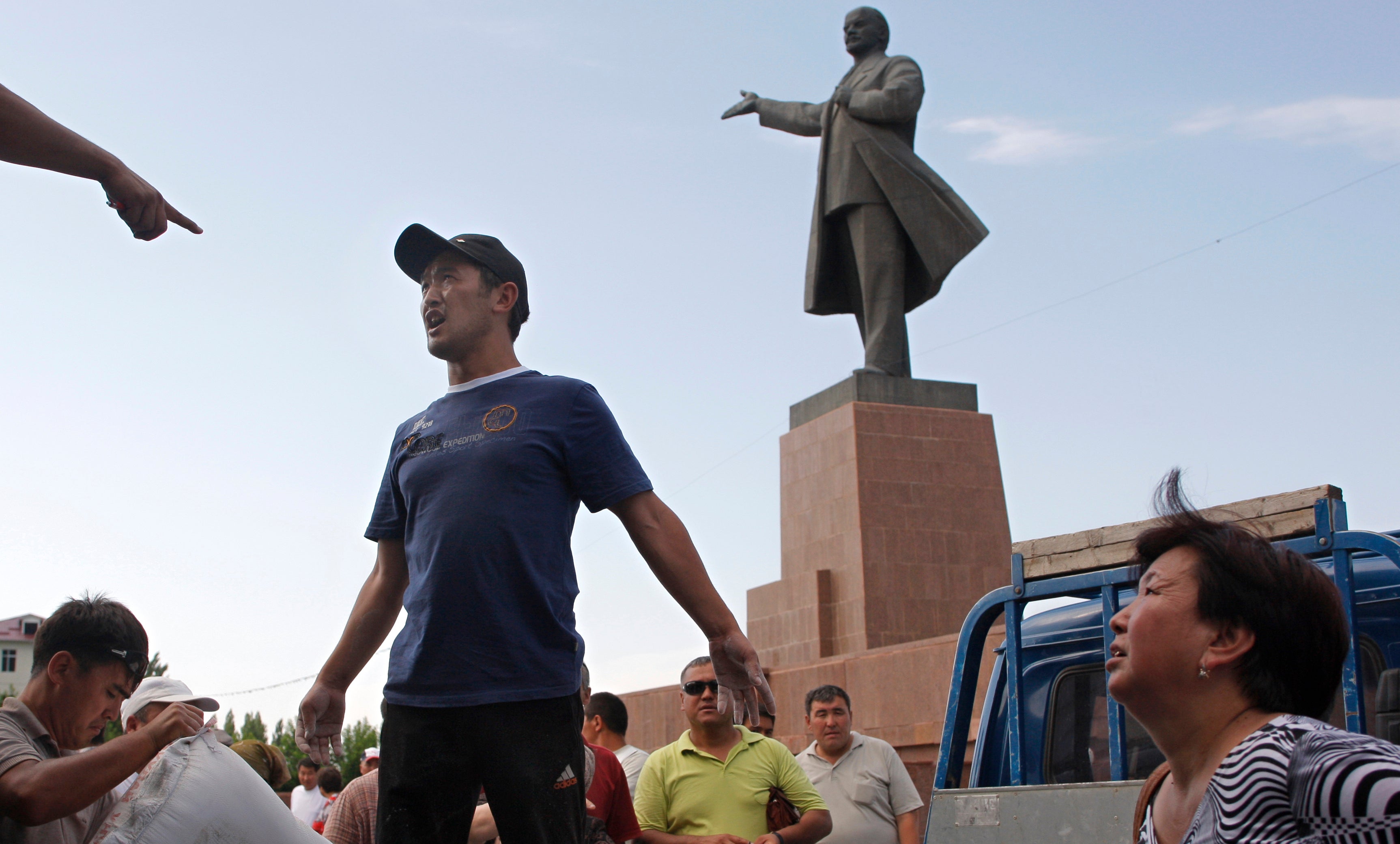 Local residents, Kyrgyz and Uzbeks, receive humanitarian aid in front of a statue of Soviet Union founder Vladimir Lenin on a central square in the southern Kyrgyz city of Osh, Kyrgyzstan, Tuesday, June 22, 2010