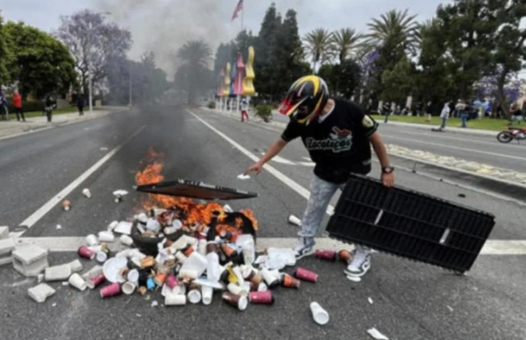 The suspect was photographed in a motorcycle helmet standing above a flaming pile of garbage at the protest.
