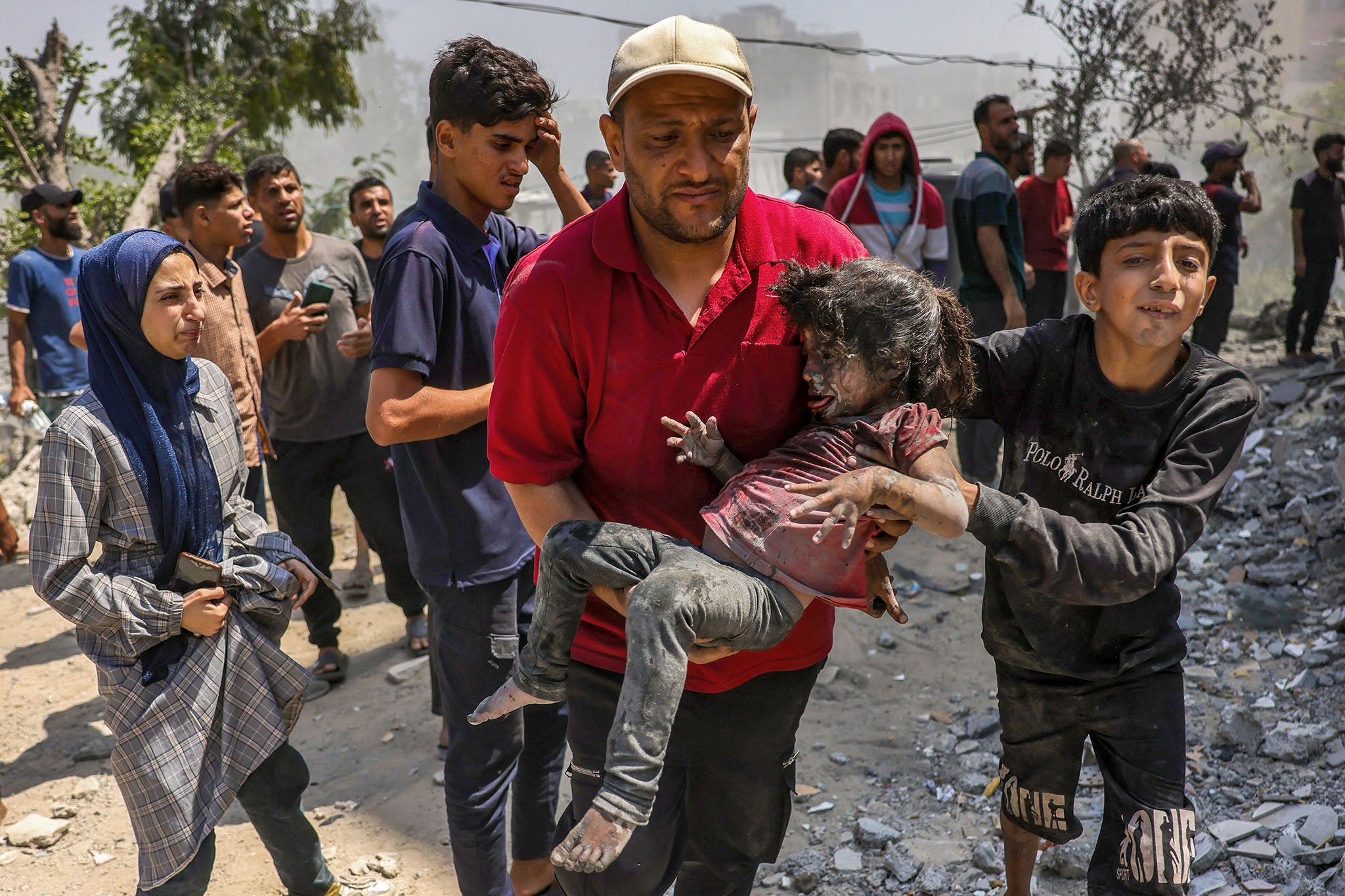 A Palestinian man carries a child pulled from the rubble of the Shaheen family home that was targeted in an Israeli strike in the Saftawi neighbourhood, west of Jabalia, in the northern Gaza Strip
