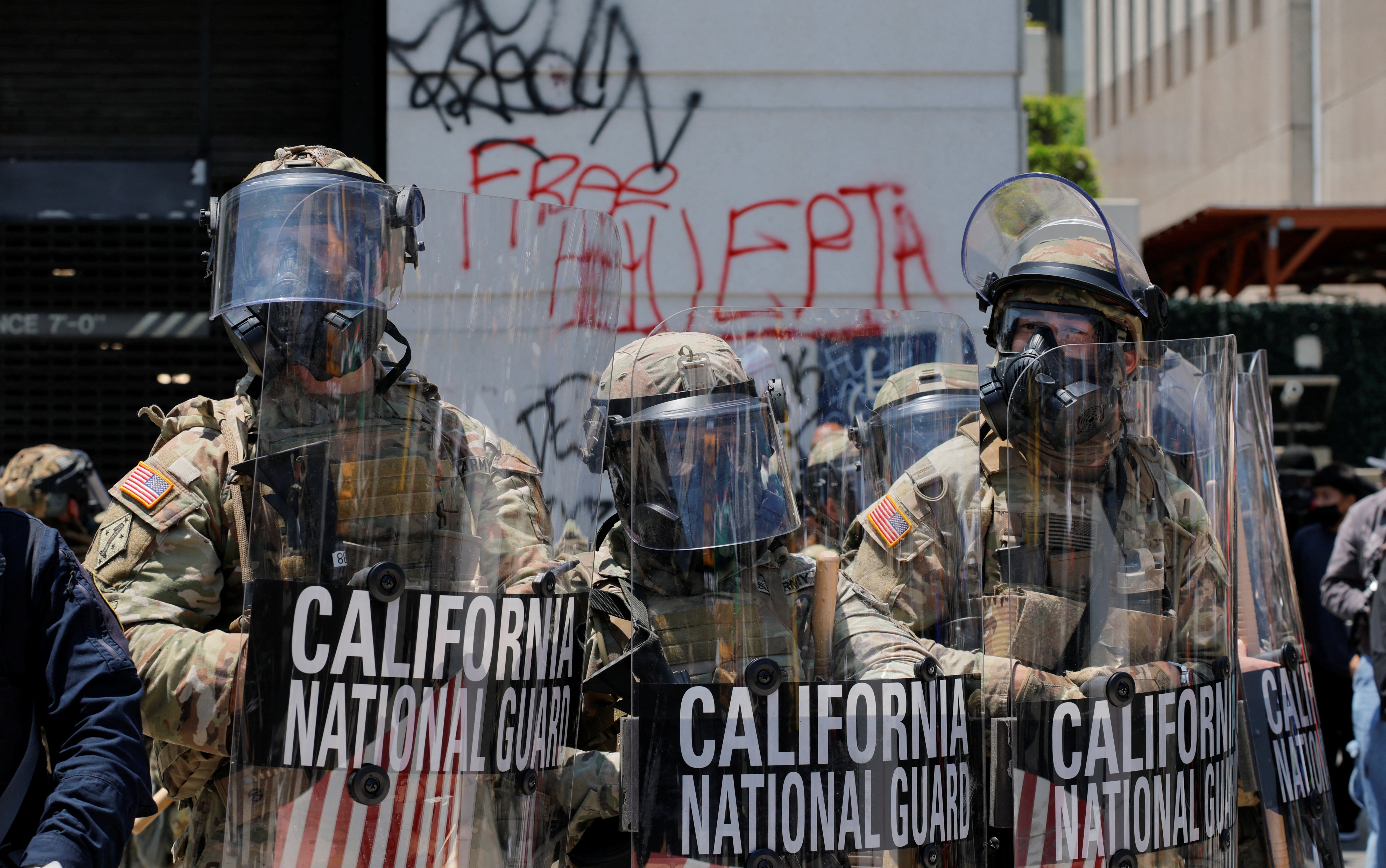 Members of the California National Guard stand together, as a demonstration against federal immigration sweeps takes place on Sunday