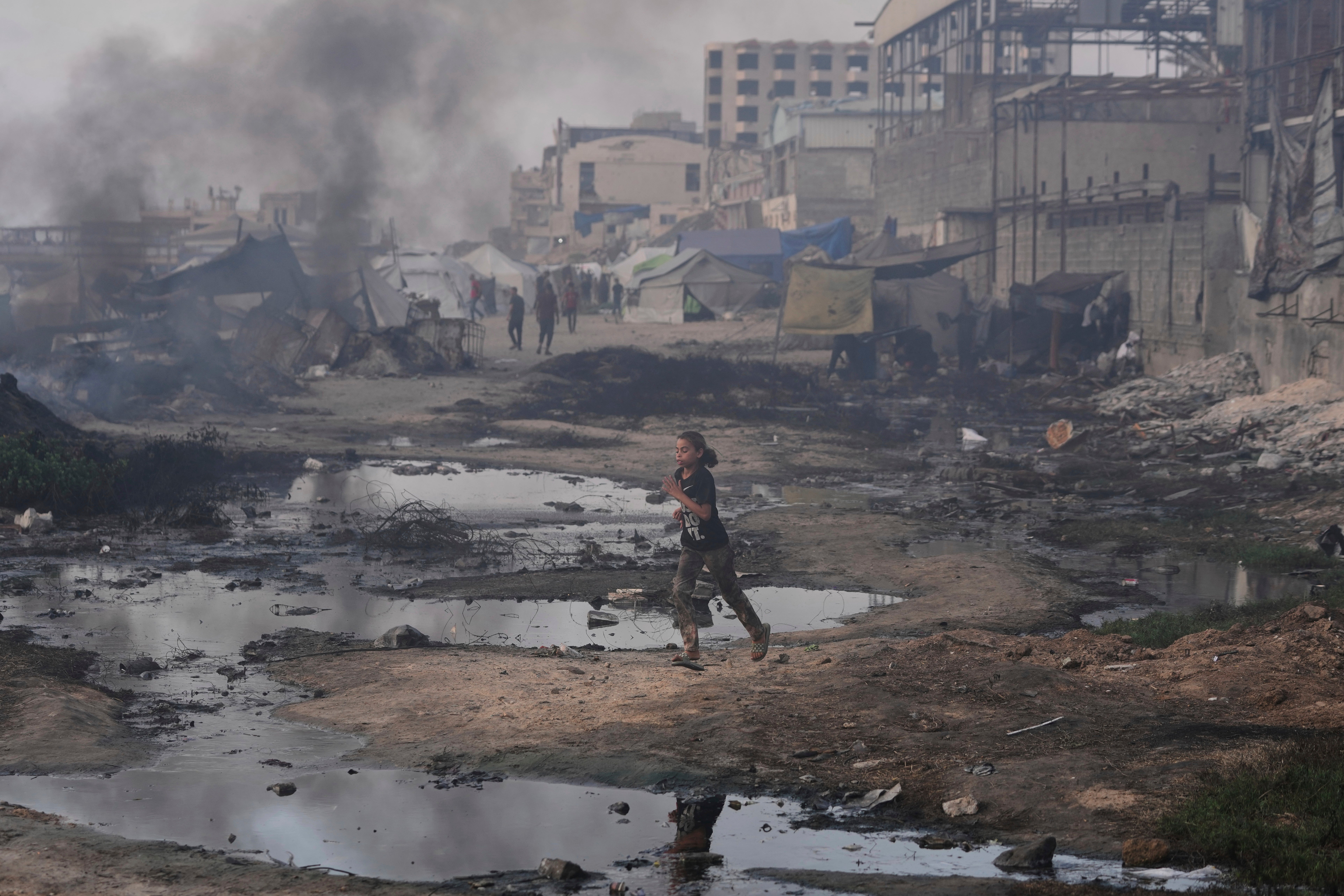 A Palestinian girl runs past the ruins of destroyed buildings along the Gaza City shoreline on 9 June