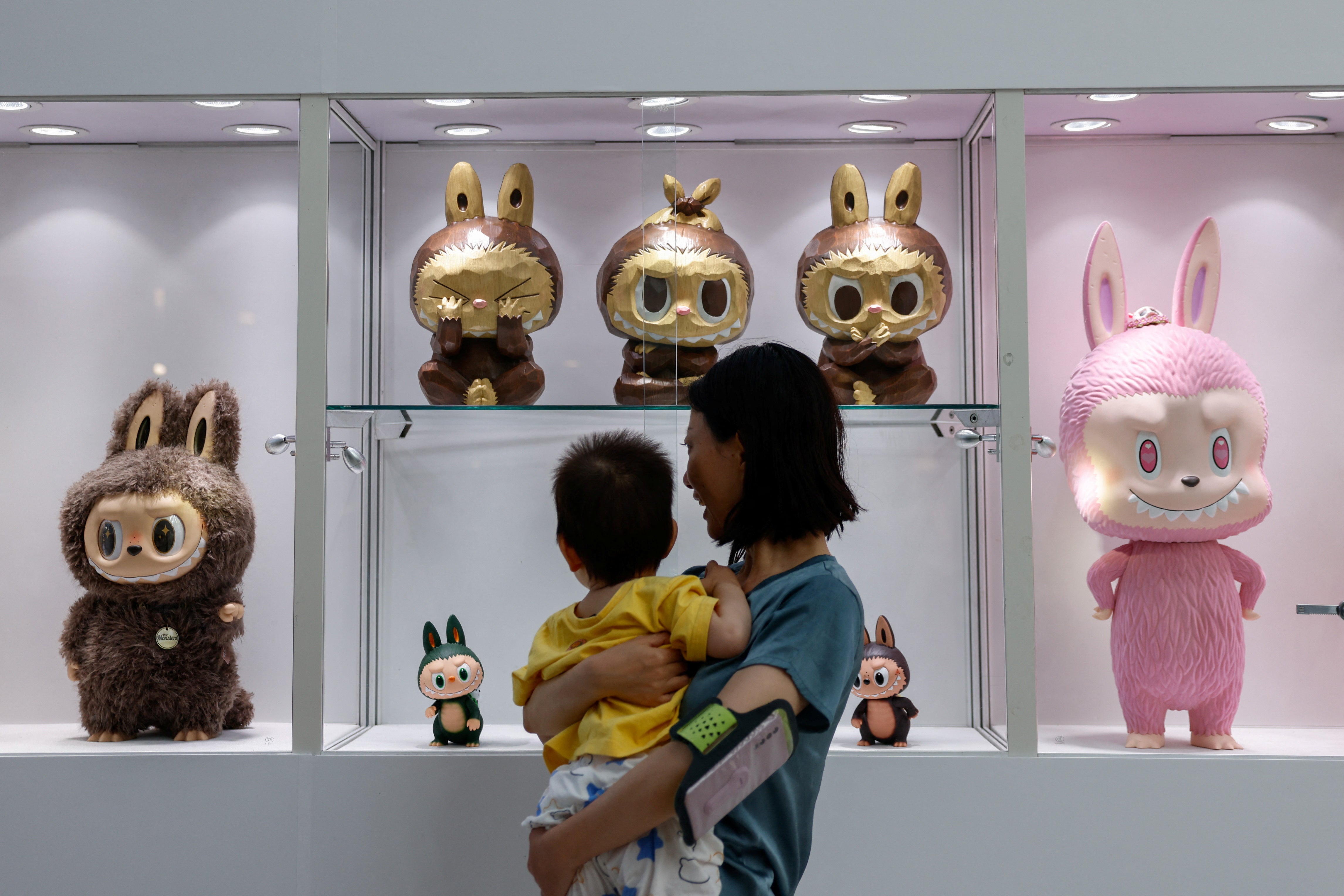 Visitors look at a set of three Labubu sculptures from a series called 'Three Wise Labubu'