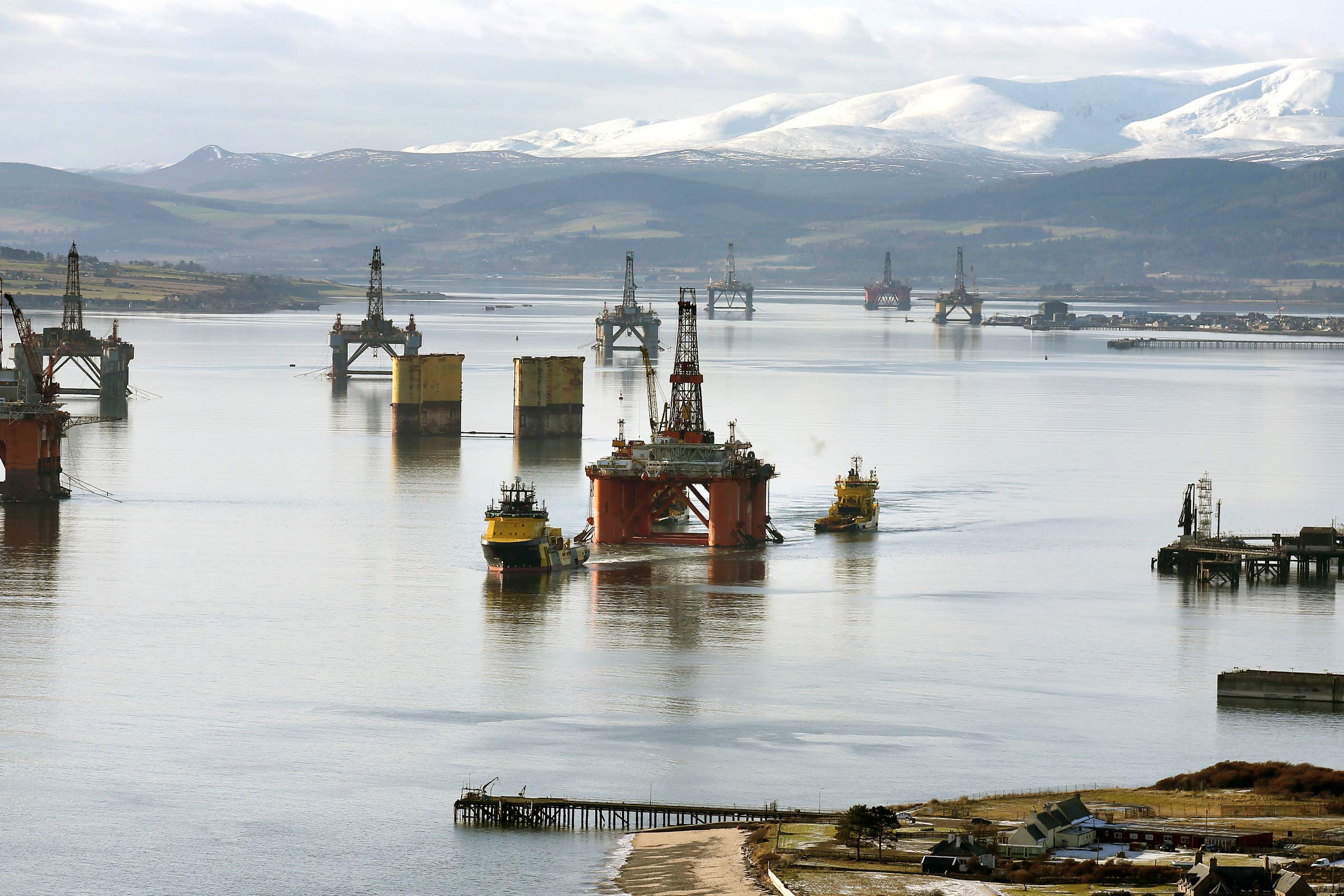 The oil platform Stena Spey (centre) is moved with tug boats amongst other rigs in the Cromarty Firth near Invergordon in Scotland (Andrew Milligan/PA)