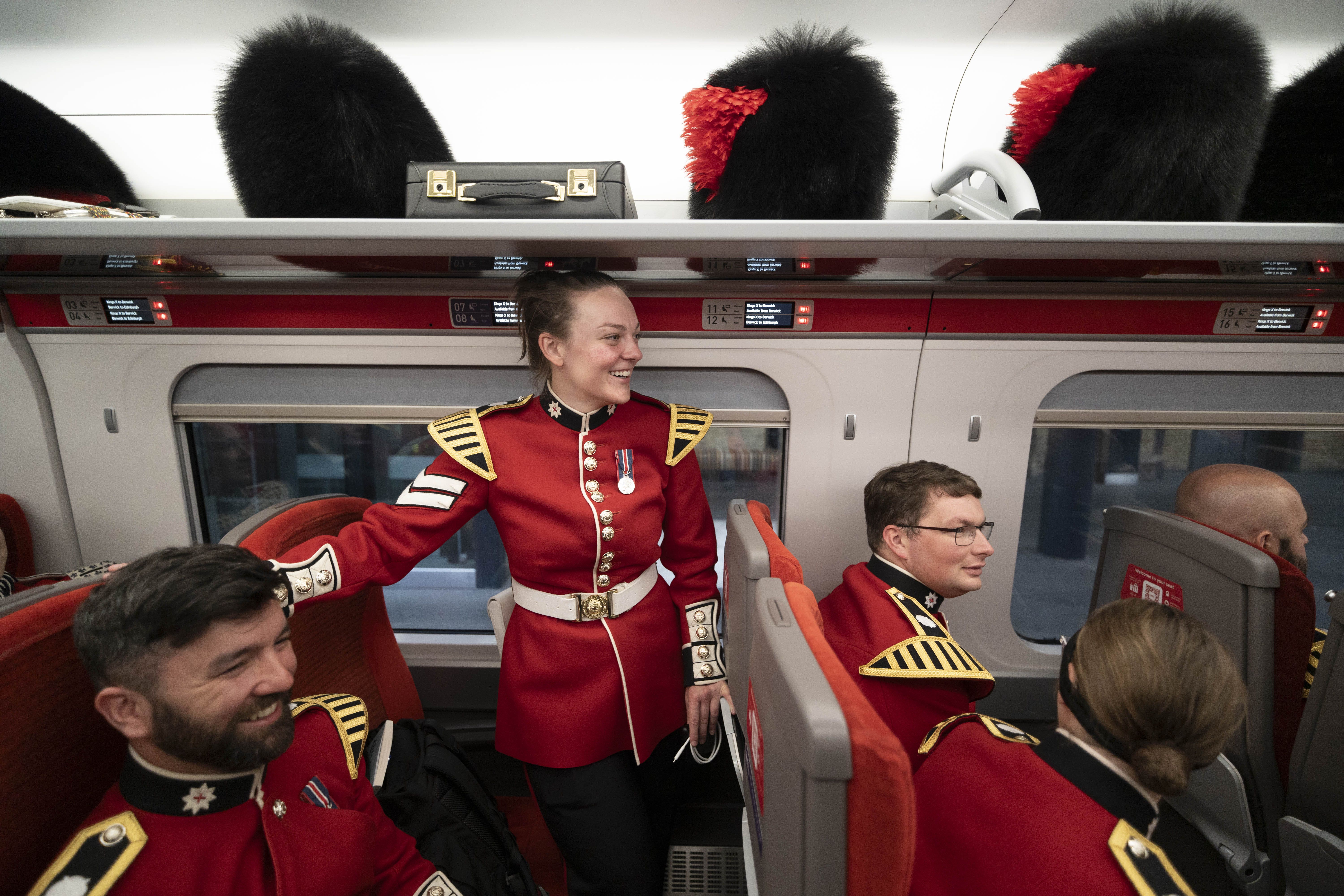 Members of The Coldstream Guards, wearing their full ceremonial dress of scarlet tunics and bearskin caps, board an LNER train at King’s Cross (Jeff Moore/PA)
