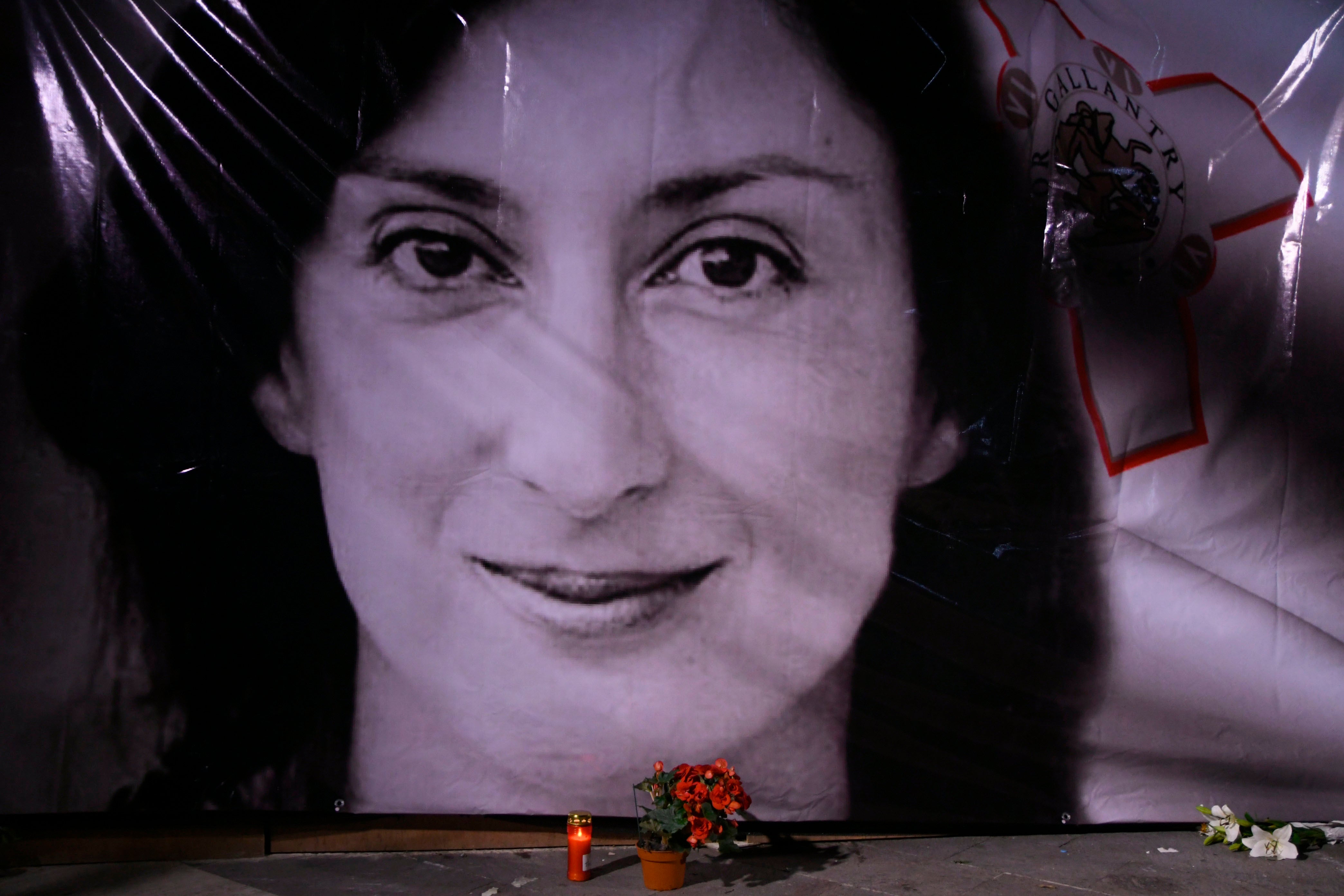 Flowers and a candle lie in front of a portrait of slain investigative journalist Daphne Caruana Galizia during a vigil outside the law courts in Valletta, Malta