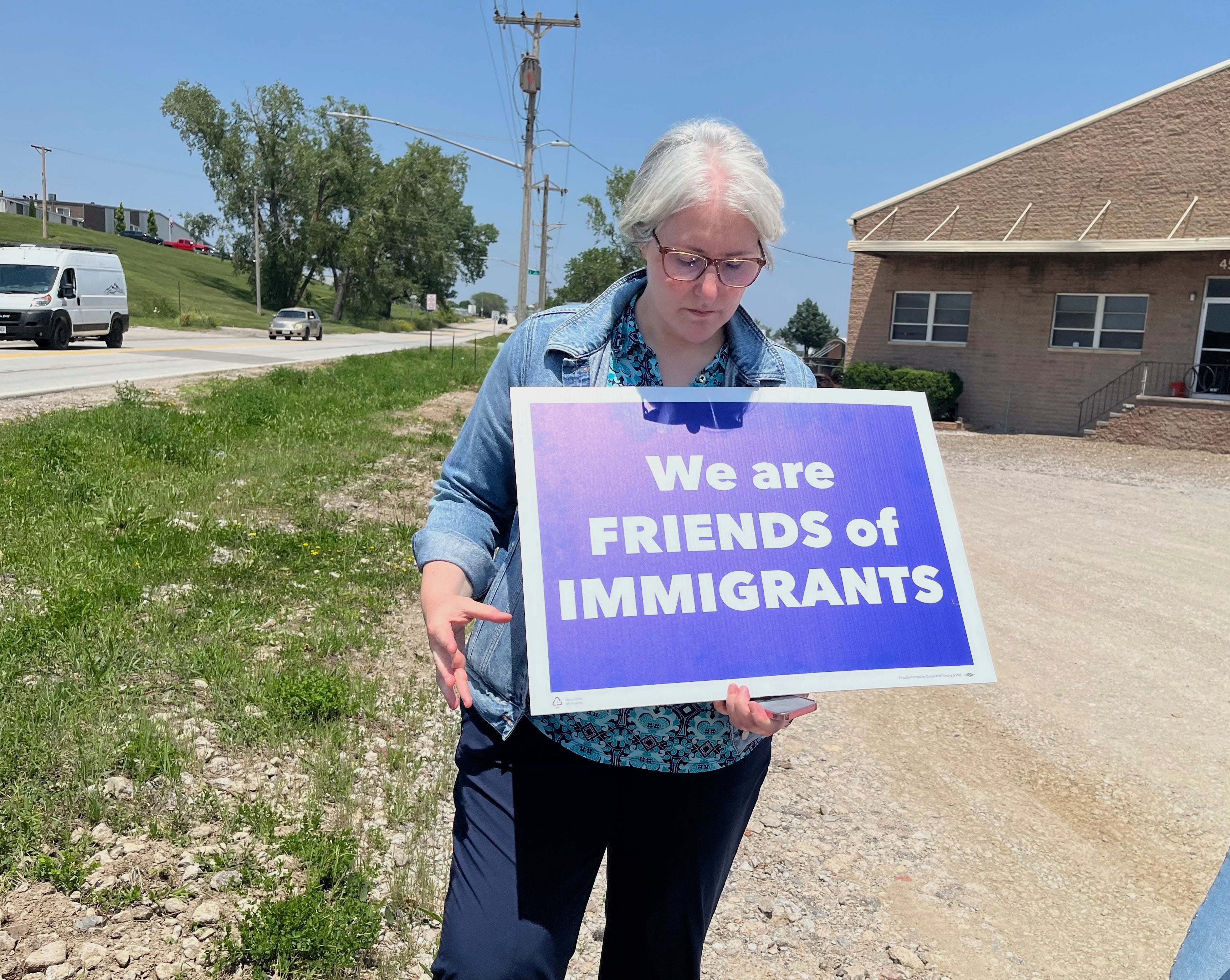 Sara Schulte-Bukowinski, a faith leader in Omaha, Neb., holds a sign protesting an immigration raid, Tuesday, June 10, 2025, at Glenn Valley Foods, a meat packaging plant in south Omaha. (AP Photo/Margery A. Beck)