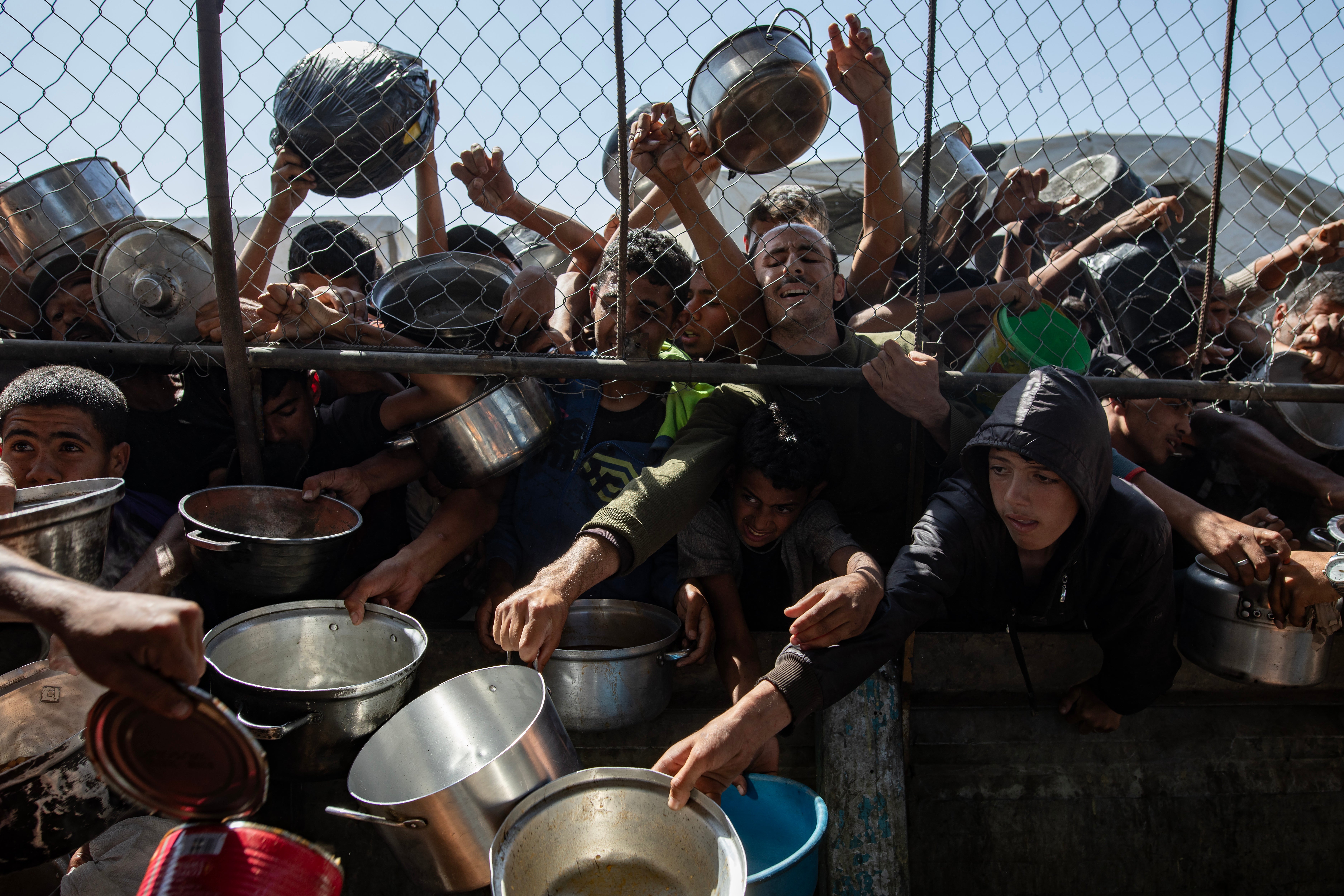 Internally displaced Palestinians gather outside a charity kitchen to receive limited rations amid a shortage of food, in Khan Younis, southern Gaza Strip, 30 May 2025