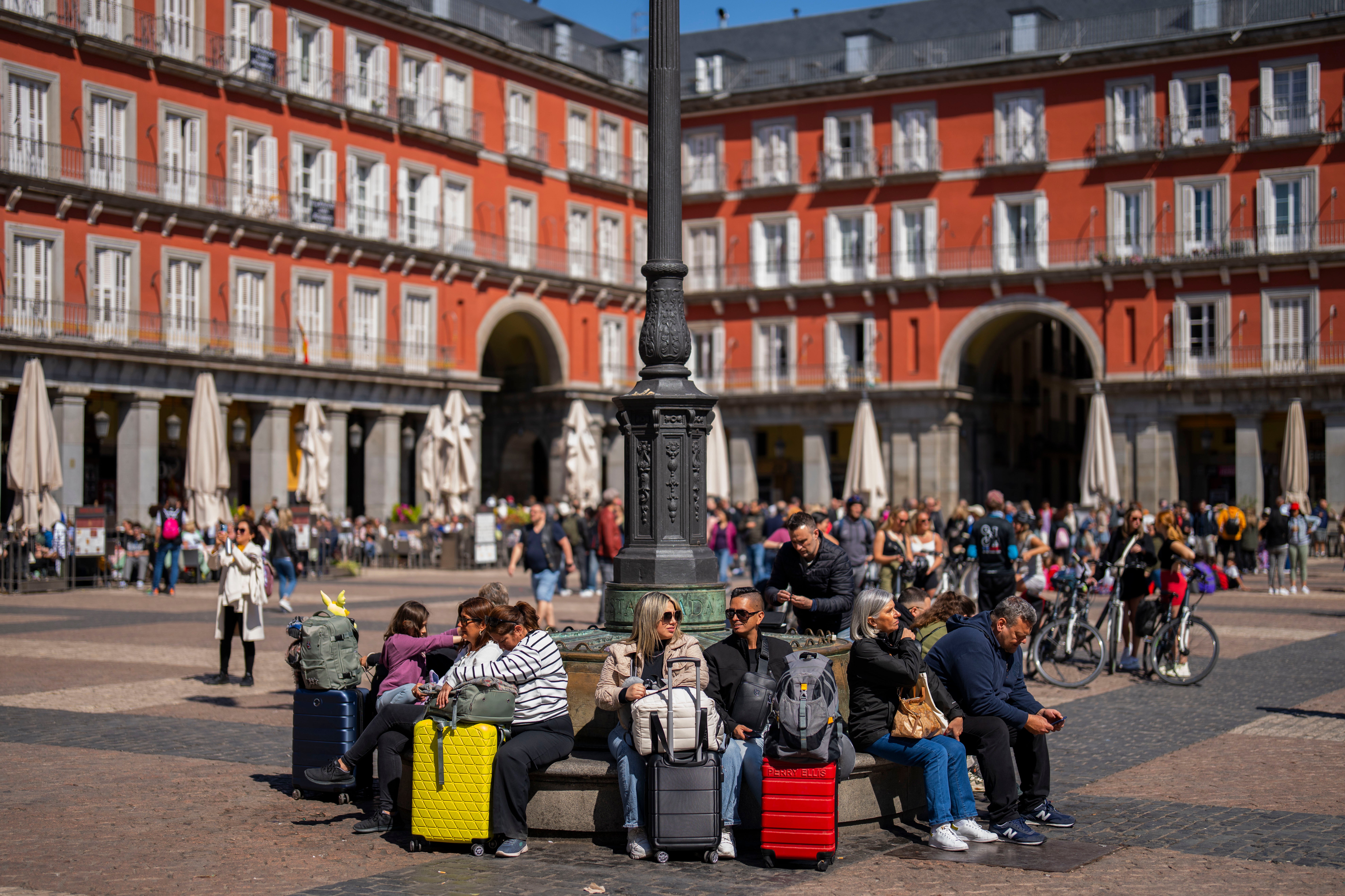 Tourists sit on a public bench at Plaza Mayor in downtown Madrid