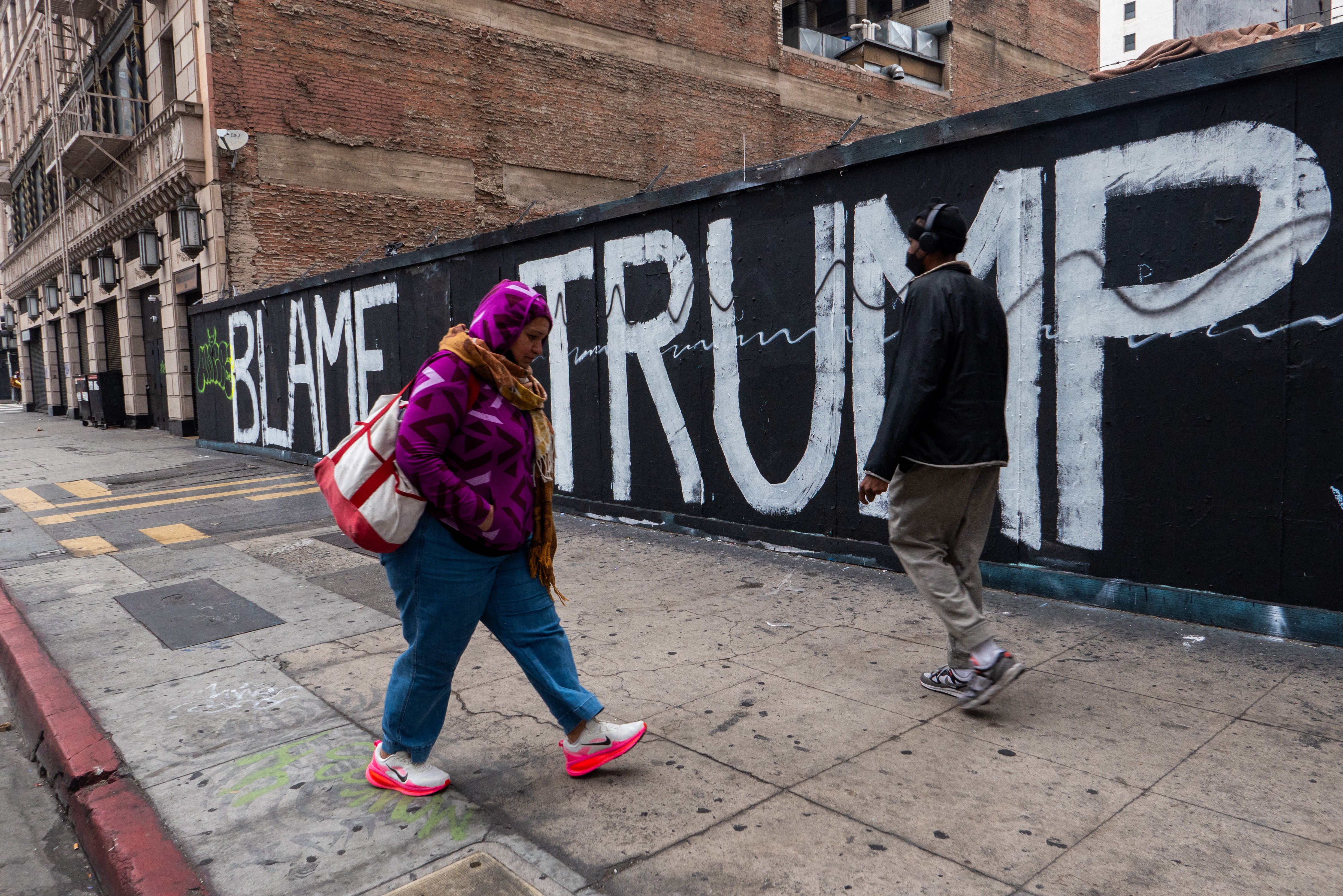 People walk through downtown Los Angeles following the lifting of an overnight curfew after numerous businesses were broken into