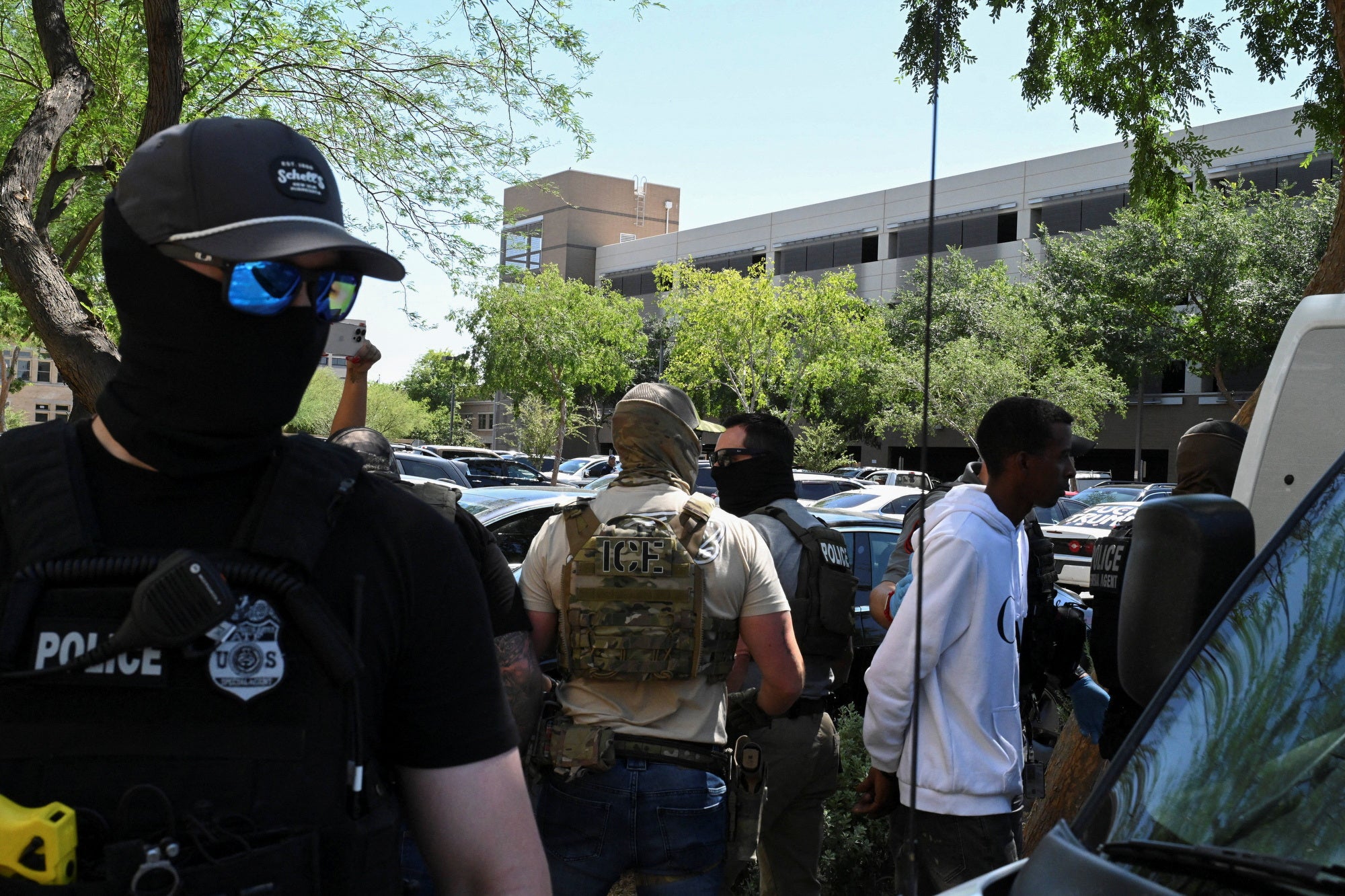 Masked law enforcement officers, including HSI and ICE agents, take people into custody at an immigration court in Phoenix, Arizona. Agents are reportedly using an app to track down immigrants and then arrest them
