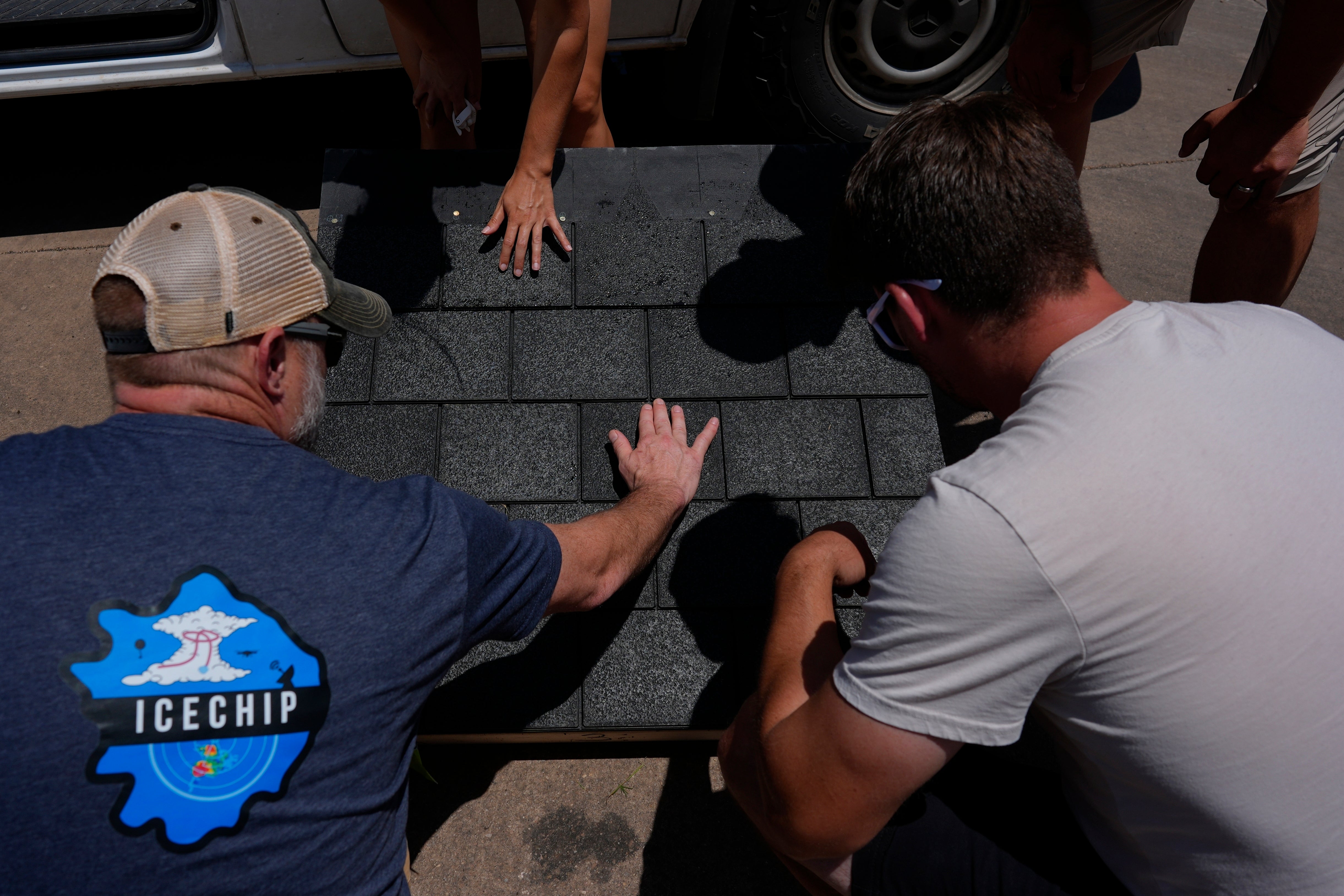 Members of Project ICECHIP inspect shingles for hail damage during an operation Friday, June 6, 2025, in Morton, Texas