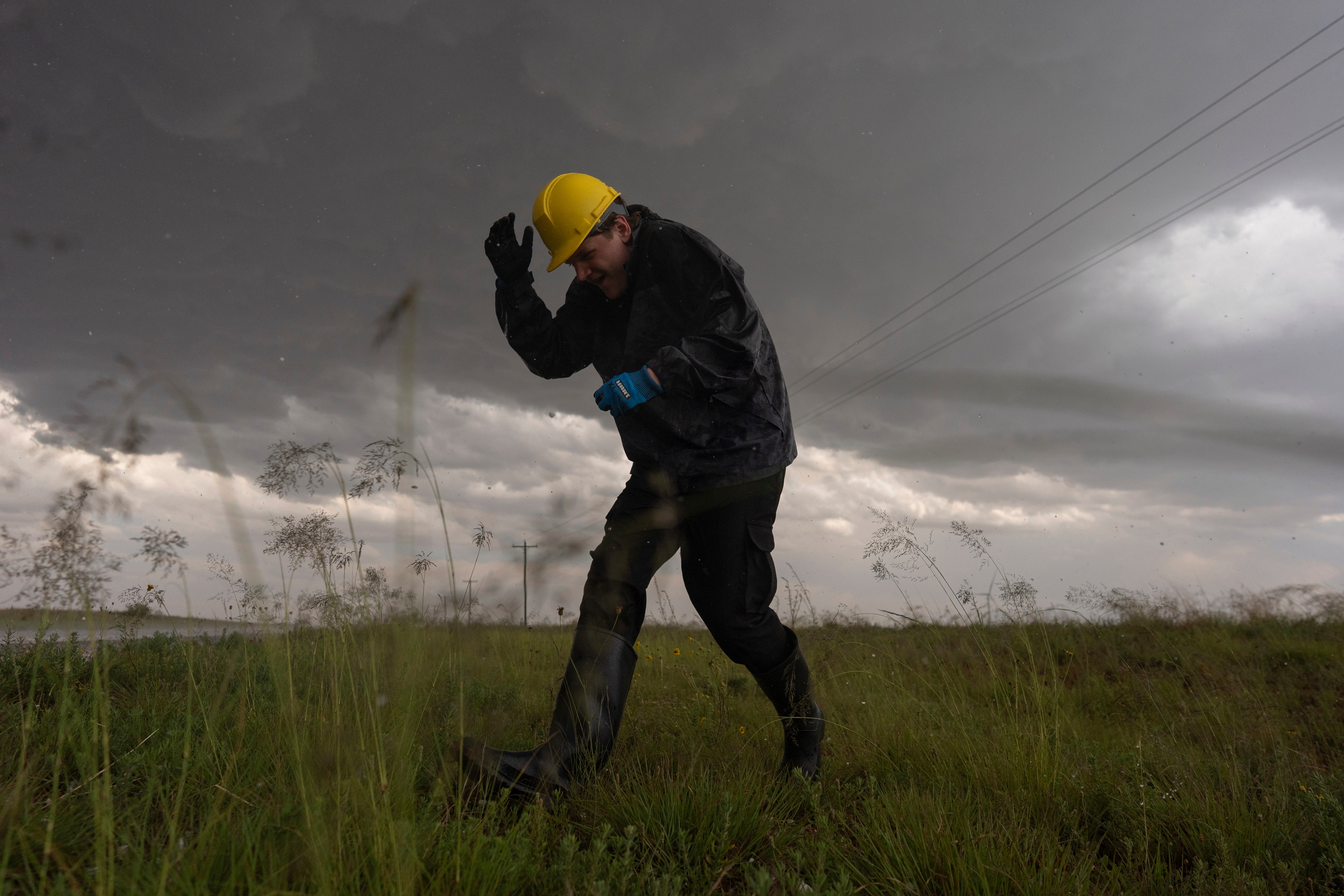 Joey Toniolo ducks from falling hail as he moves back to Northern Illinois University's Husky Hail Hunter vehicle during a Project ICECHIP operation