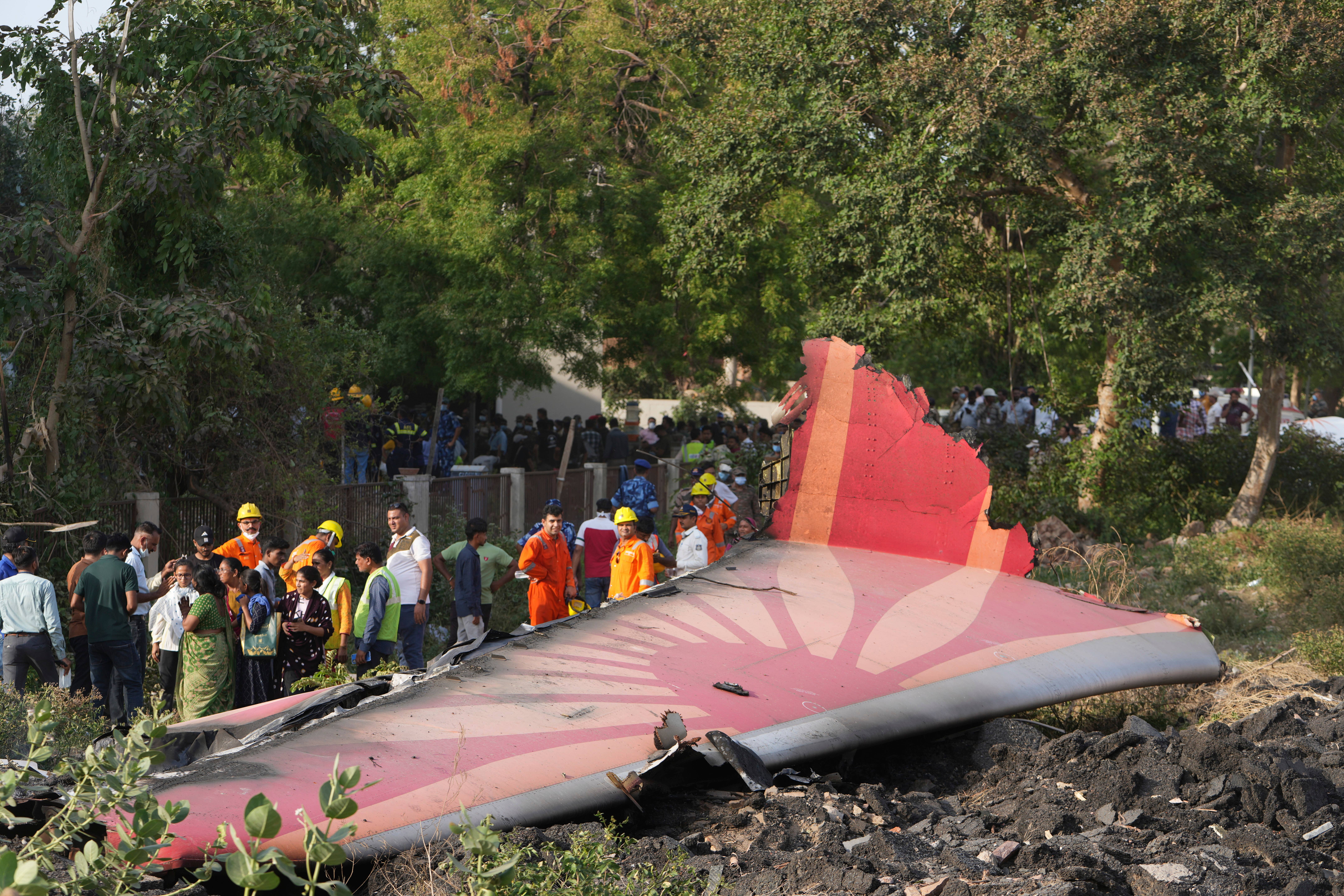 People stand around the debris of a plane after it crashed in Ahmedabad