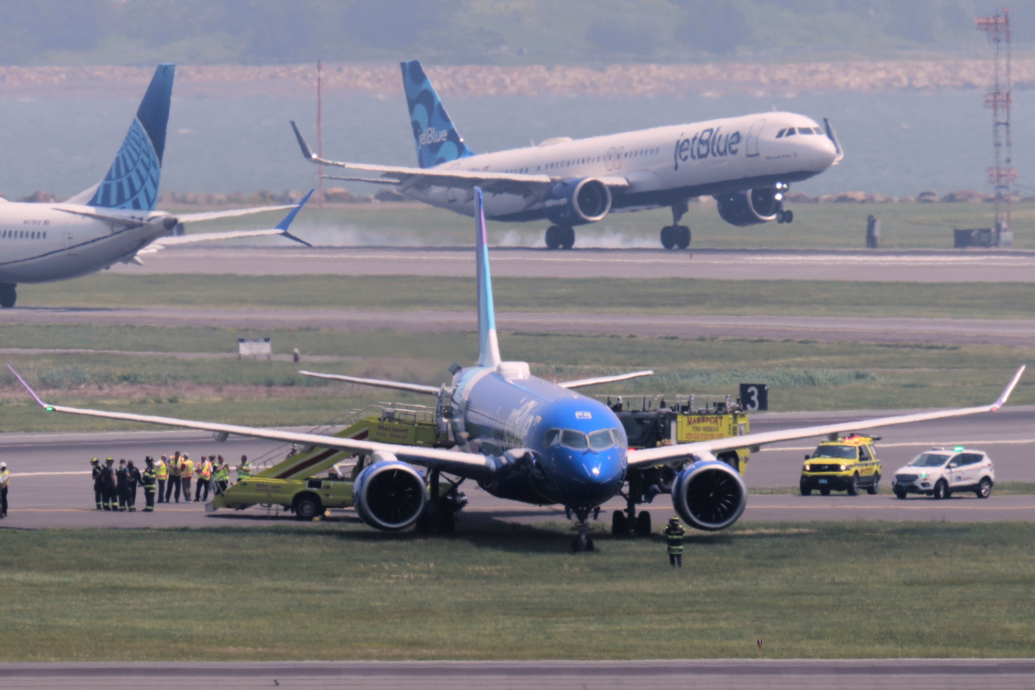 Emergency responders surround a JetBlue plane which rolled off a runway onto a grass area while landing at Logan Airport on Thursday