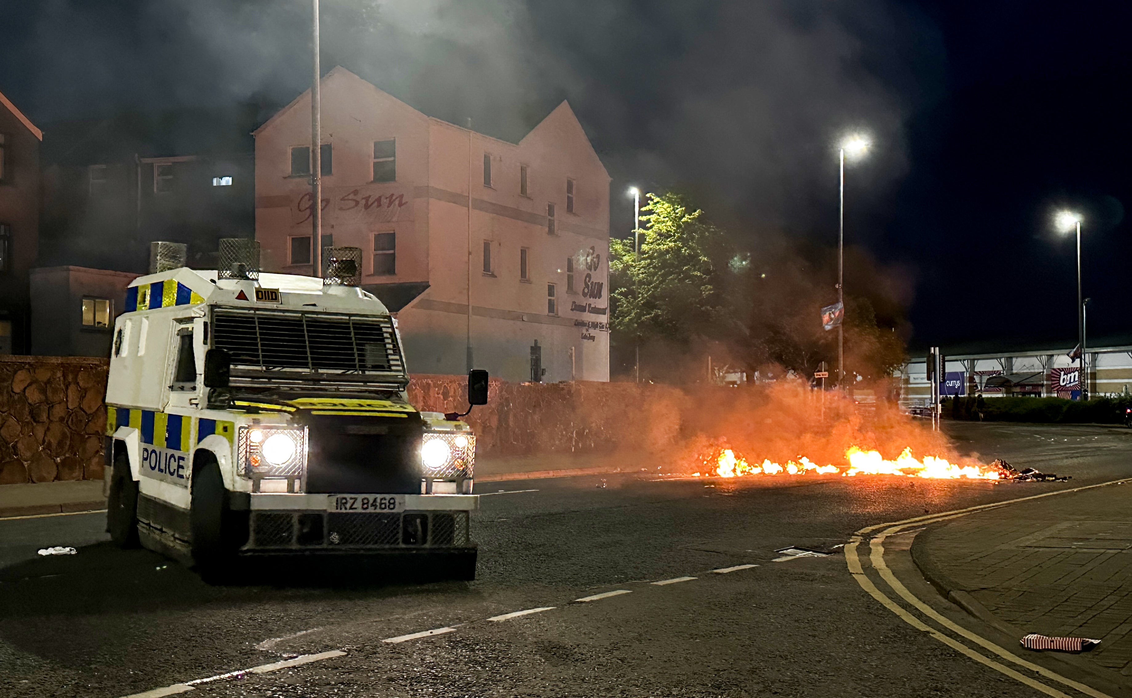 A PSNI vehicle near to debris on fire during disorder in Ballymena