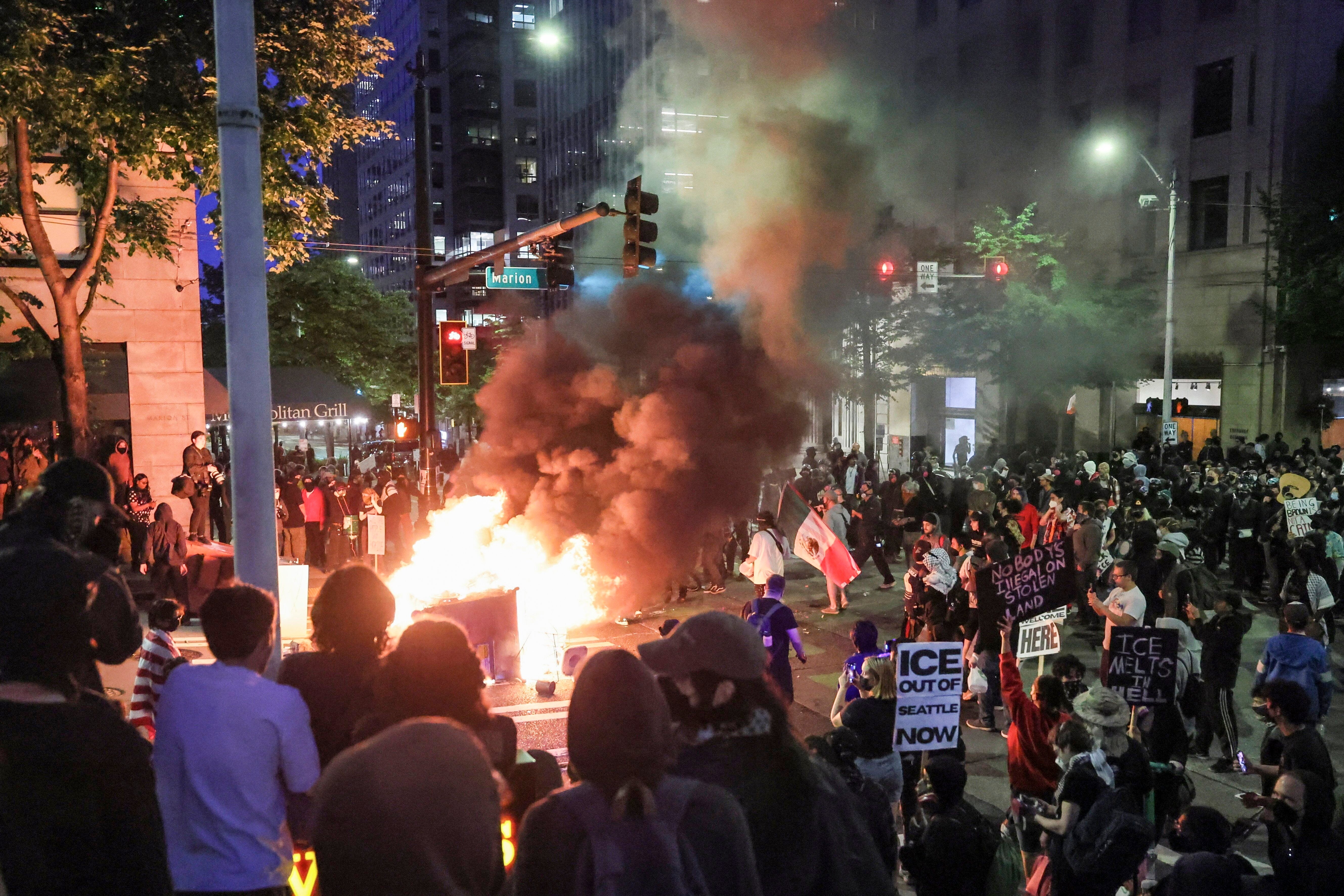 Protesters light a fire outside the Henry M. Jackson Federal Building in downtown Seattle Wednesday