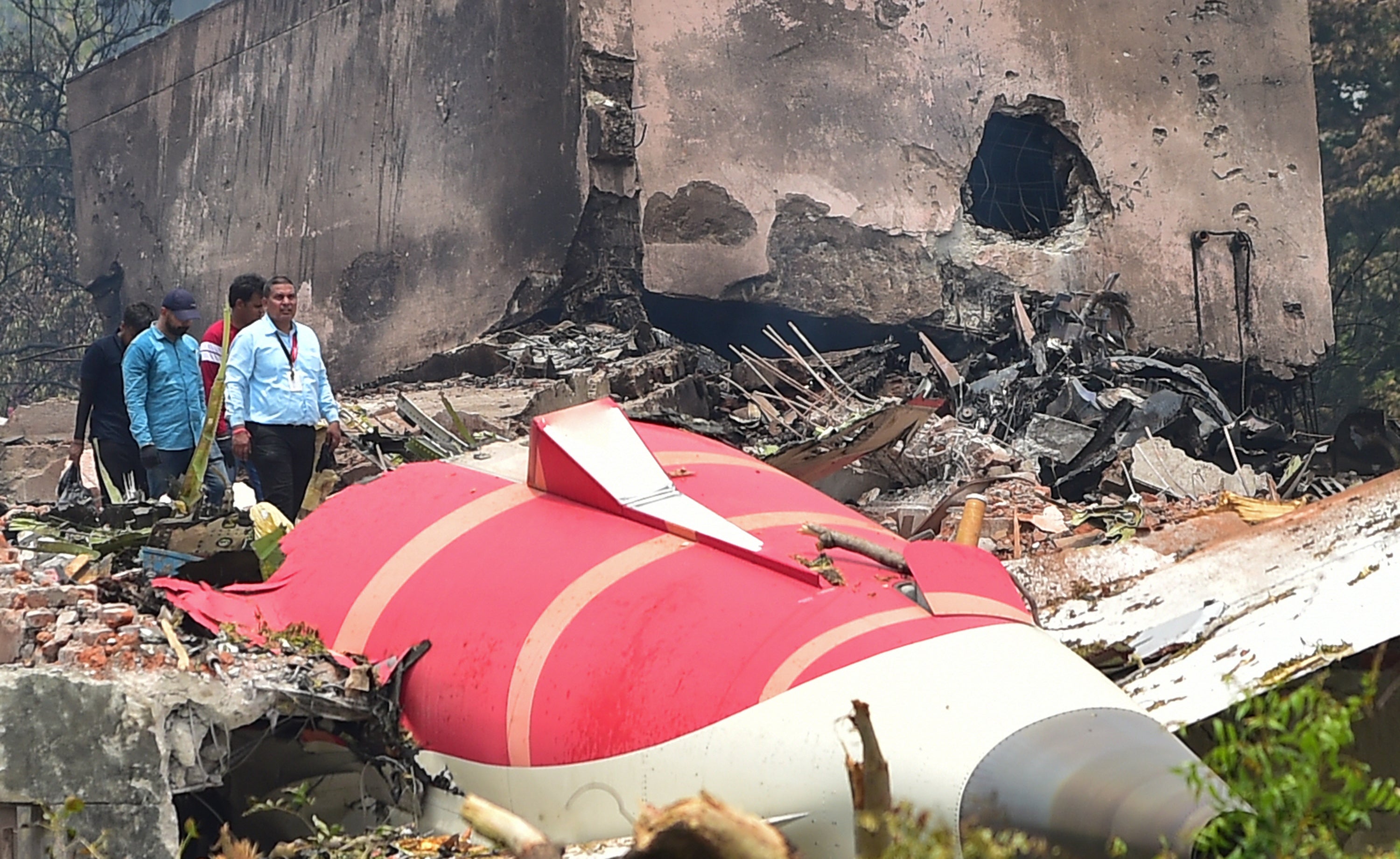 Investigative officials stand at the site of Air India Boeing 787 which crashed on Thursday