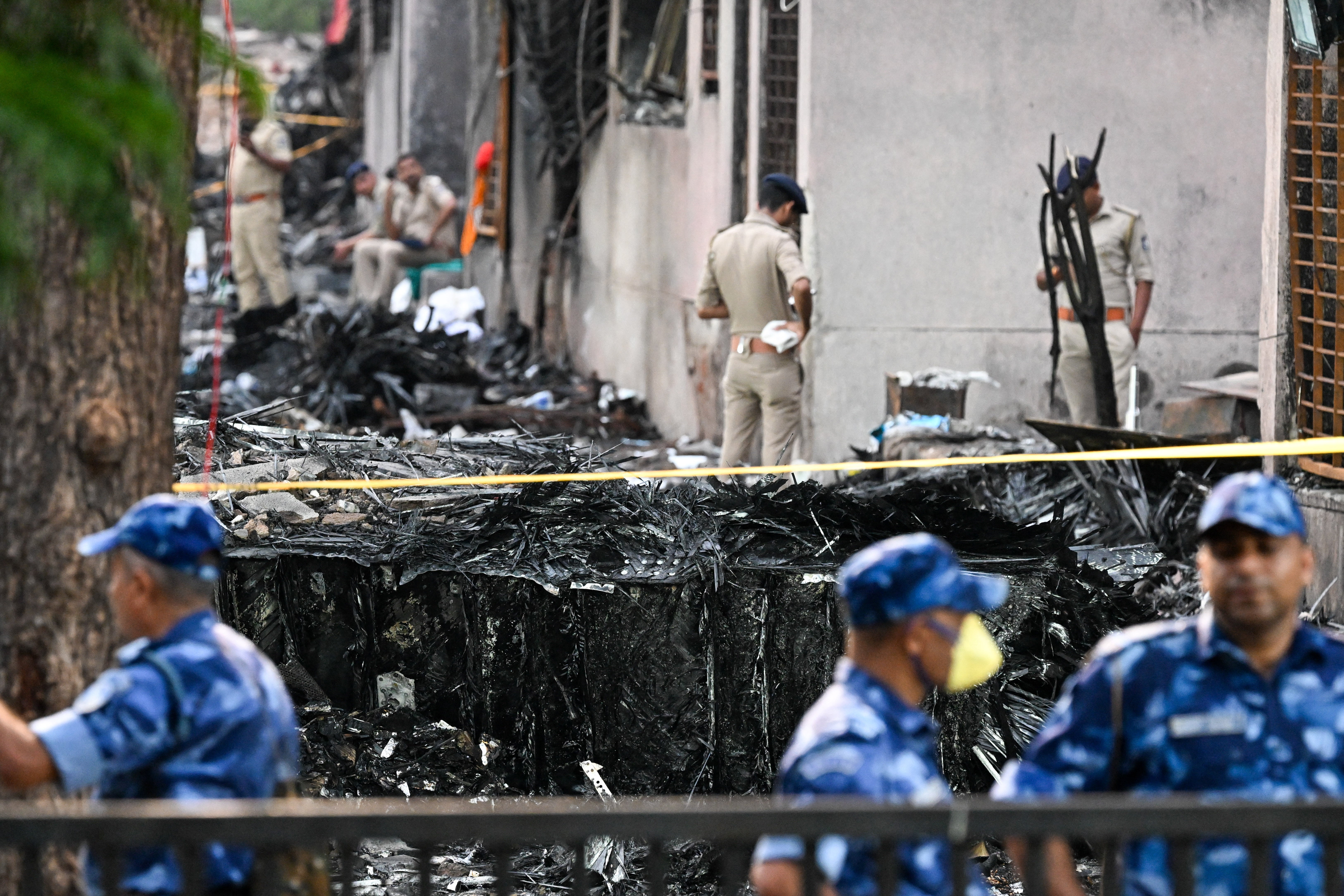 Police stand guard near wreckage at the site after Air India flight 171 crashed in a residential area near the airport in Ahmedabad