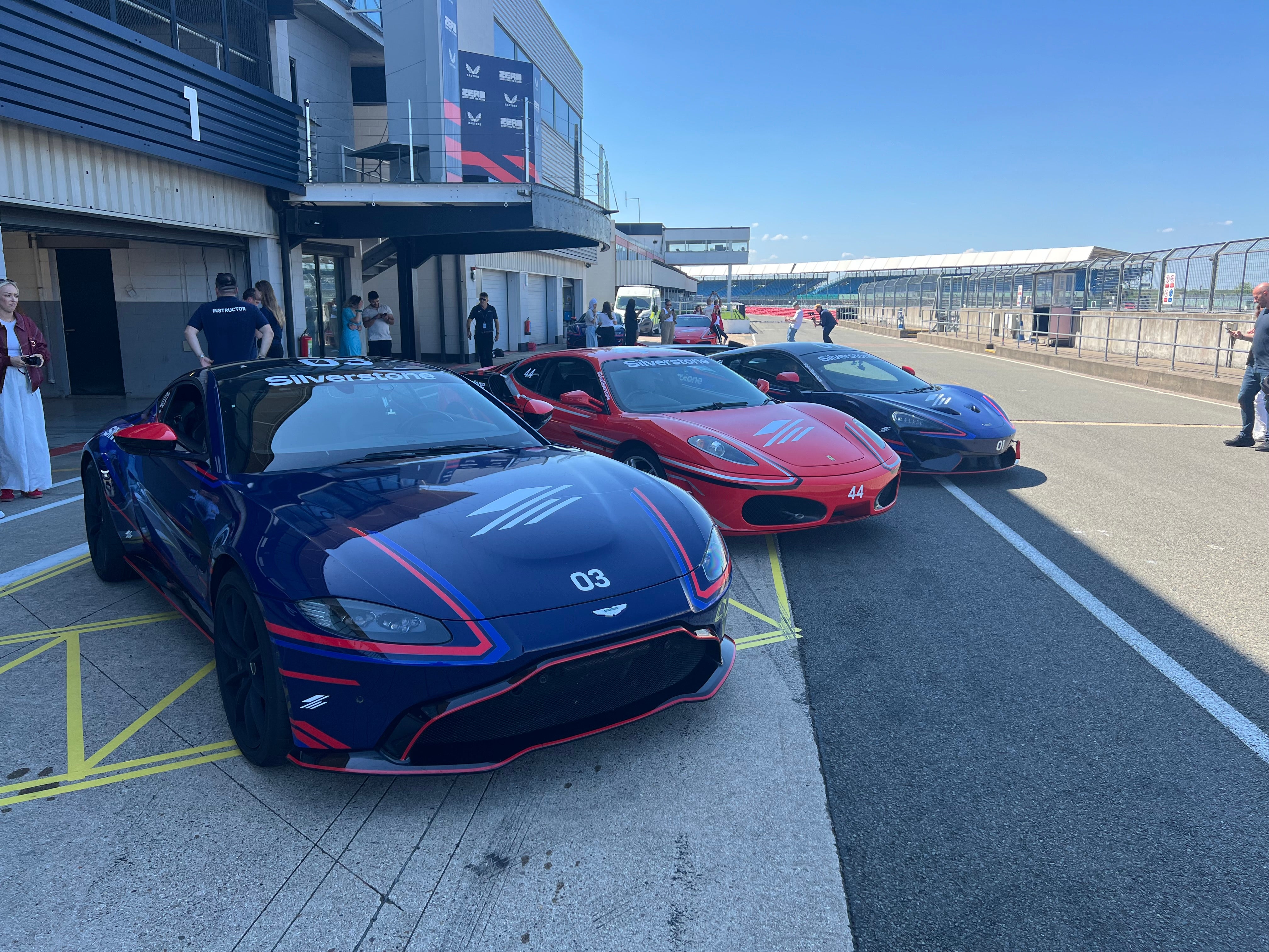 An Aston Martin, Ferrari and McLaren in the National Circuit pits at Silverstone