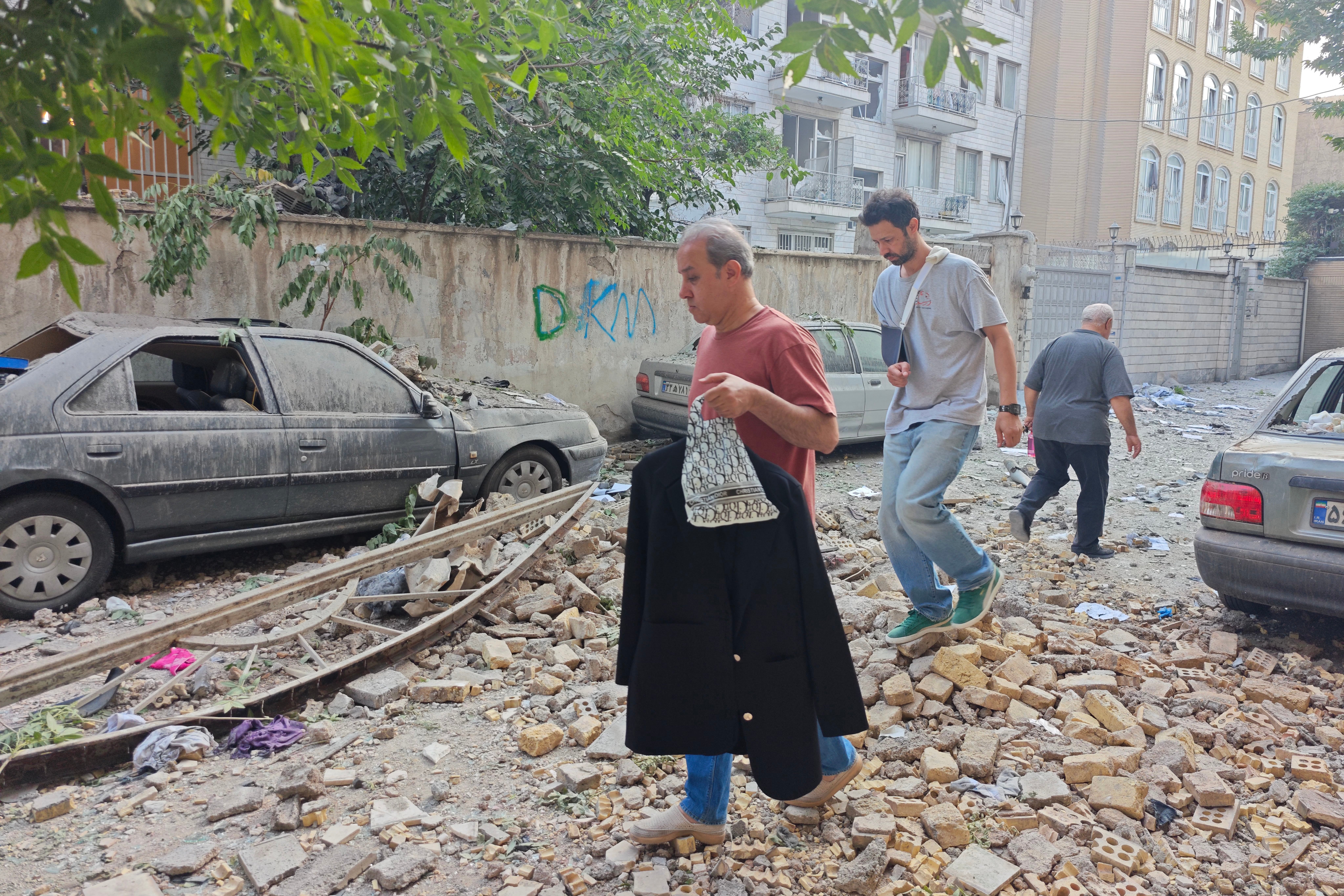 Residents in Tehran walk through the rubble on Friday morning