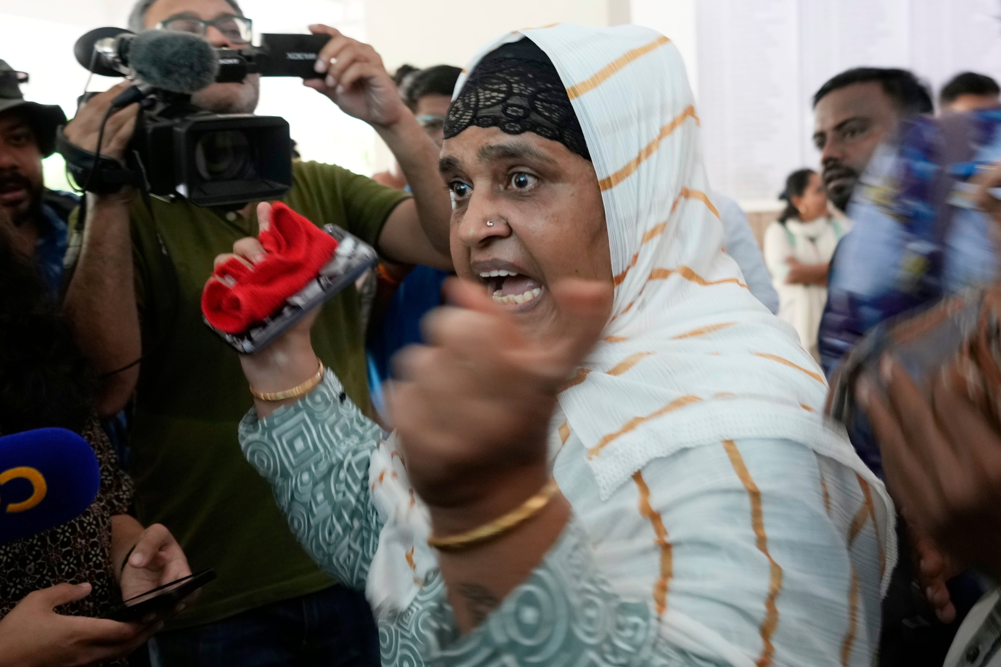 Salma Rafiq Memon, in white scarf, gestures angrily as she speaks to media personnel while waiting for the bodies of four relatives who died in the Air India plane crash, at a hospital in Ahmedabad, India, Saturday