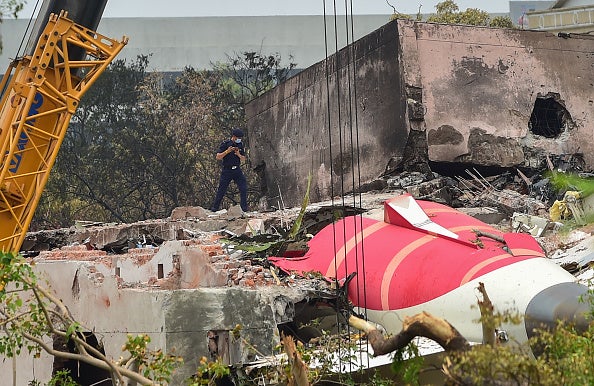 Investigators at the scene as a crane retrieves part of the fuselage of the Air India Boeing 787
