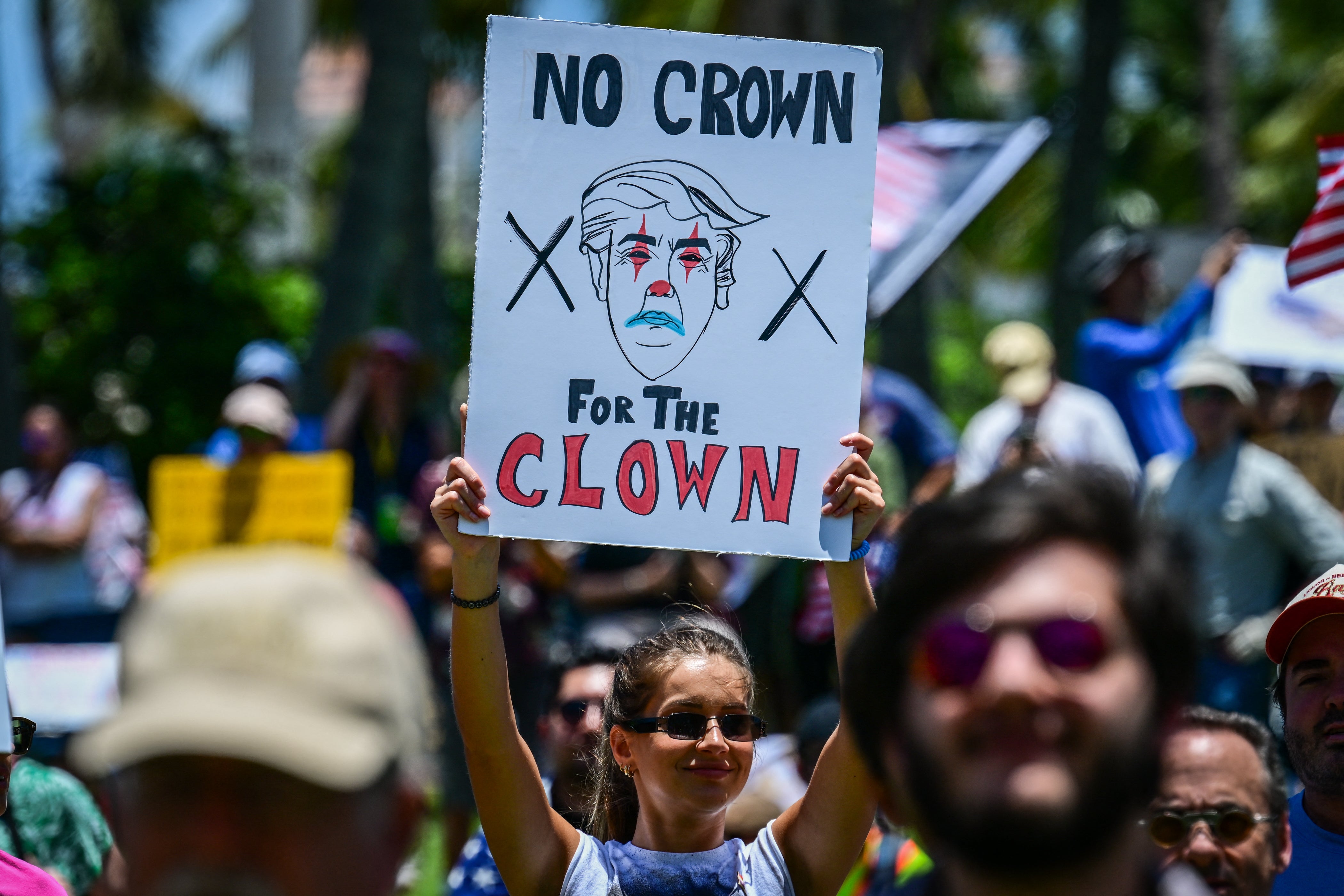 A demonstrator holds a sign protesting against the Trump administration during the “No Kings” rally near the president’s Mar-a-Lago home in West Palm Beach, Florida, on June 14 2025