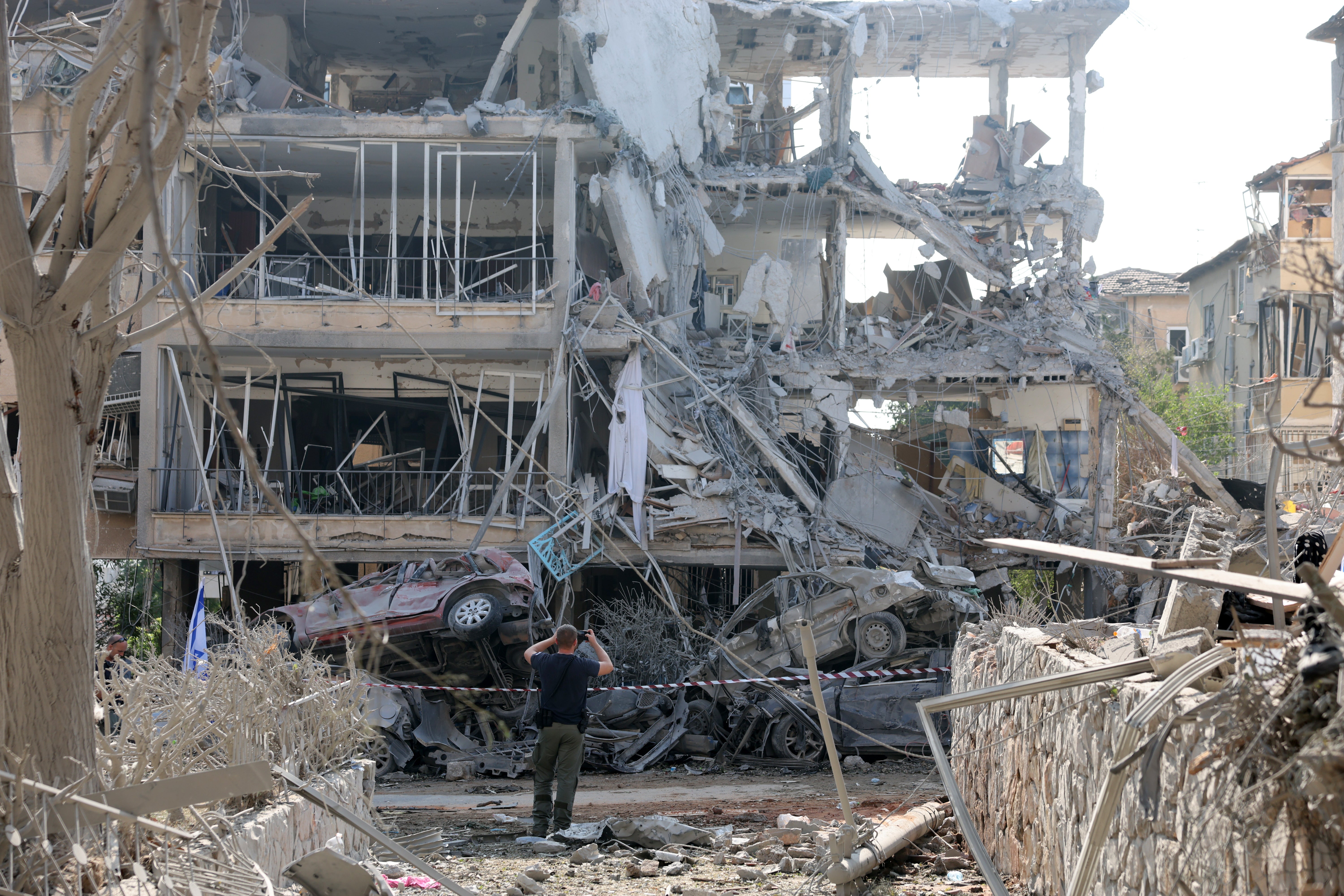 An Israeli police officer inspects a damaged residential building after a ballistic missile strike in Ramat Gan
