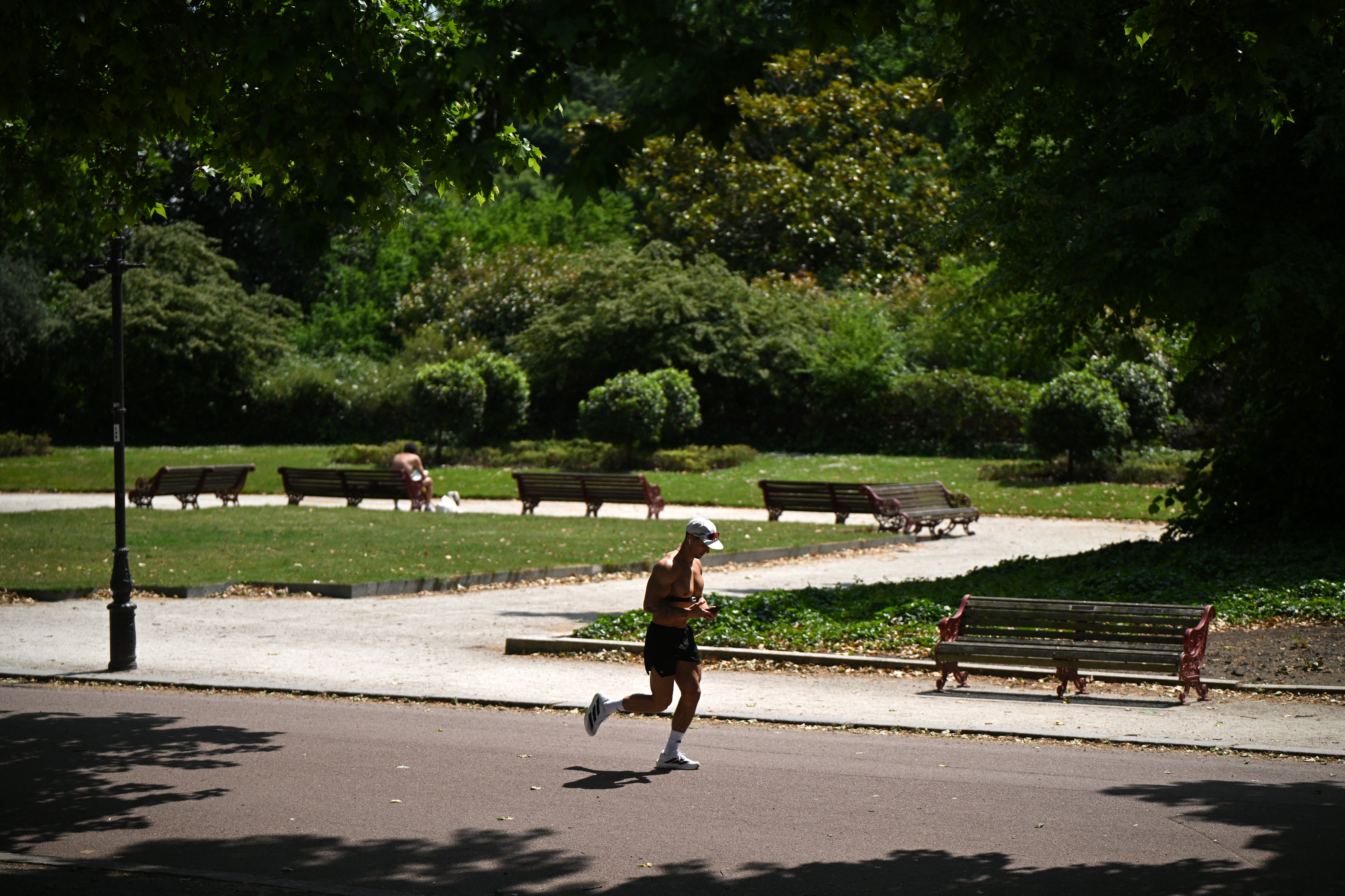 A person jogs in the sunshine in Battersea Park, south west London