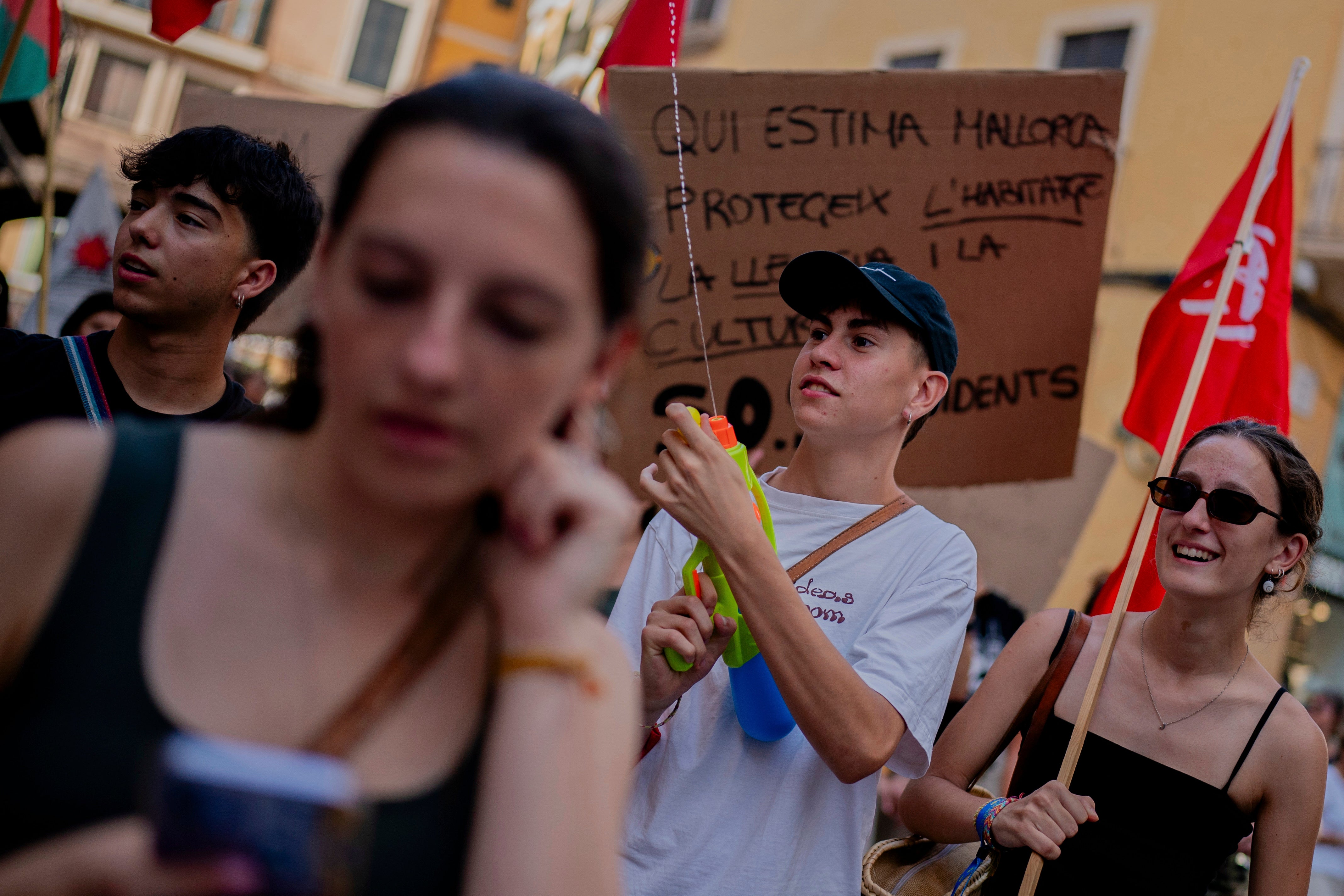 A protester holds a water gun during a protest against overtourism in the Balearic island of Mallorca, Spain, Sunday, June 15, 2025. (AP Photo/Joan Mateu Parra)