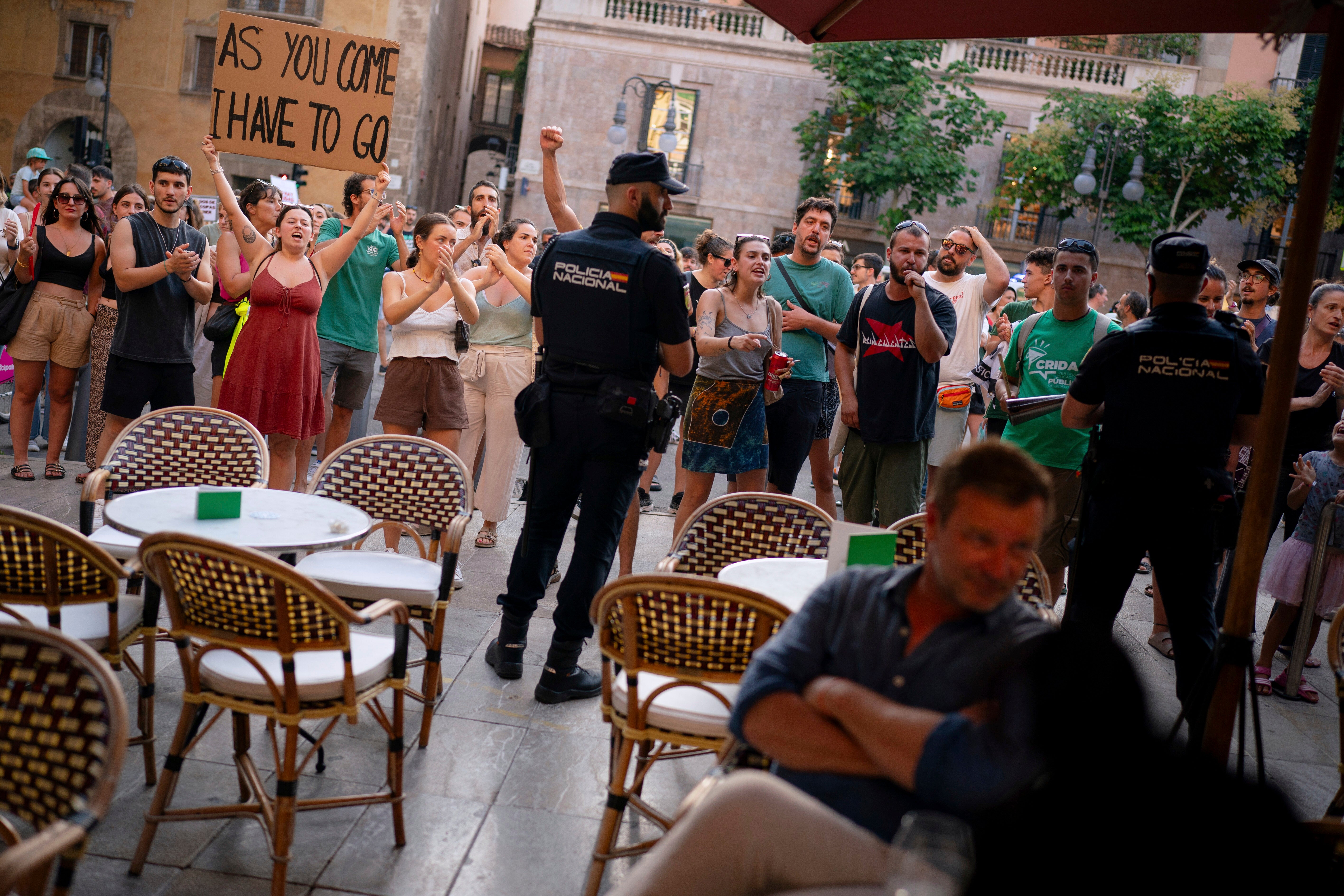 People demonstrate next to a restaurant during a protest against overtourism in the Balearic island of Mallorca, Spain, Sunday, June 15, 2025. (AP Photo/Joan Mateu Parra)