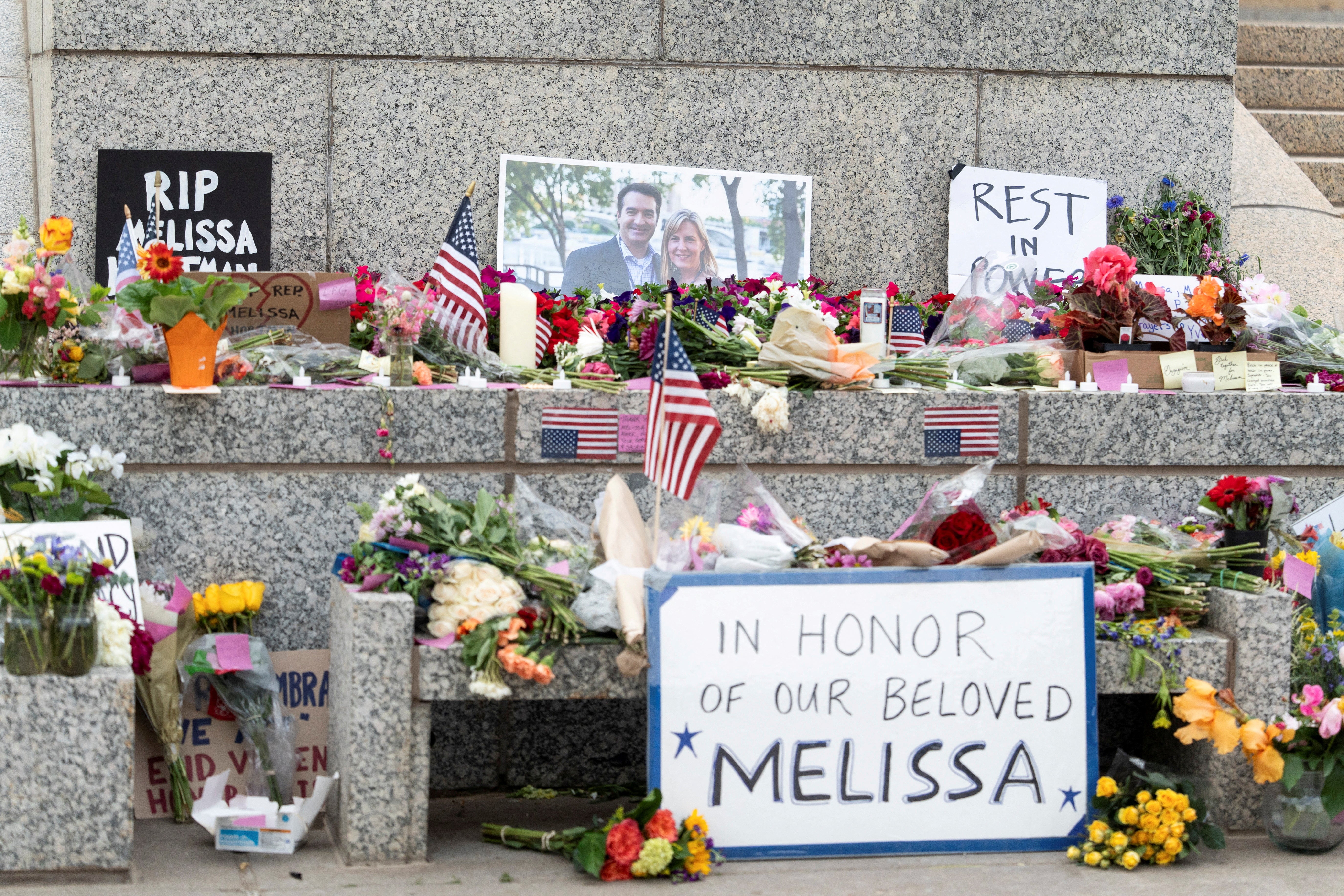 Flowers and hand-written messages adorn the base of a statue in tribute to Melissa Hortman and her husband, Mark