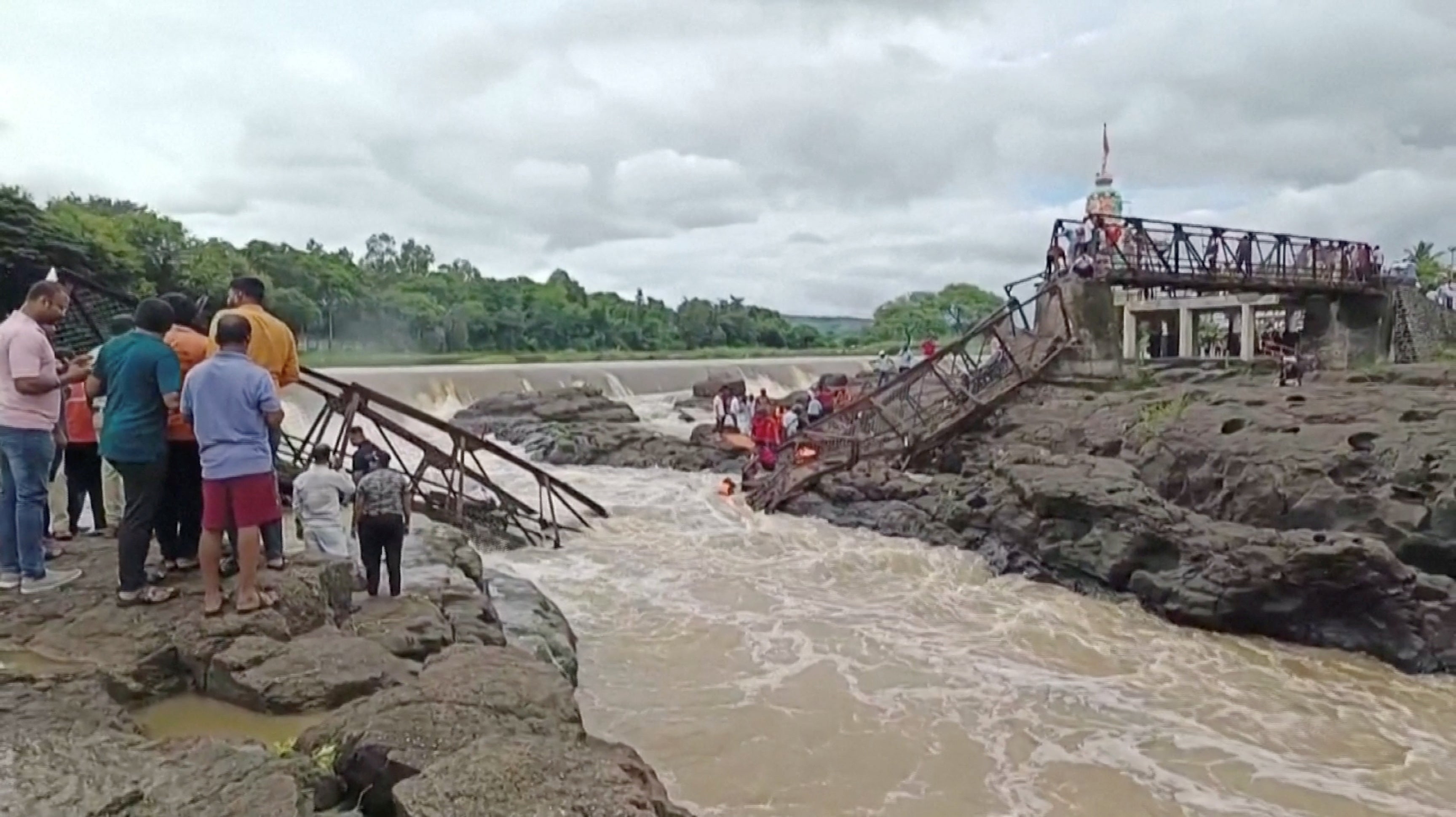People gather following a bridge collapse over the Indrayani river in the western Indian city, in Pune