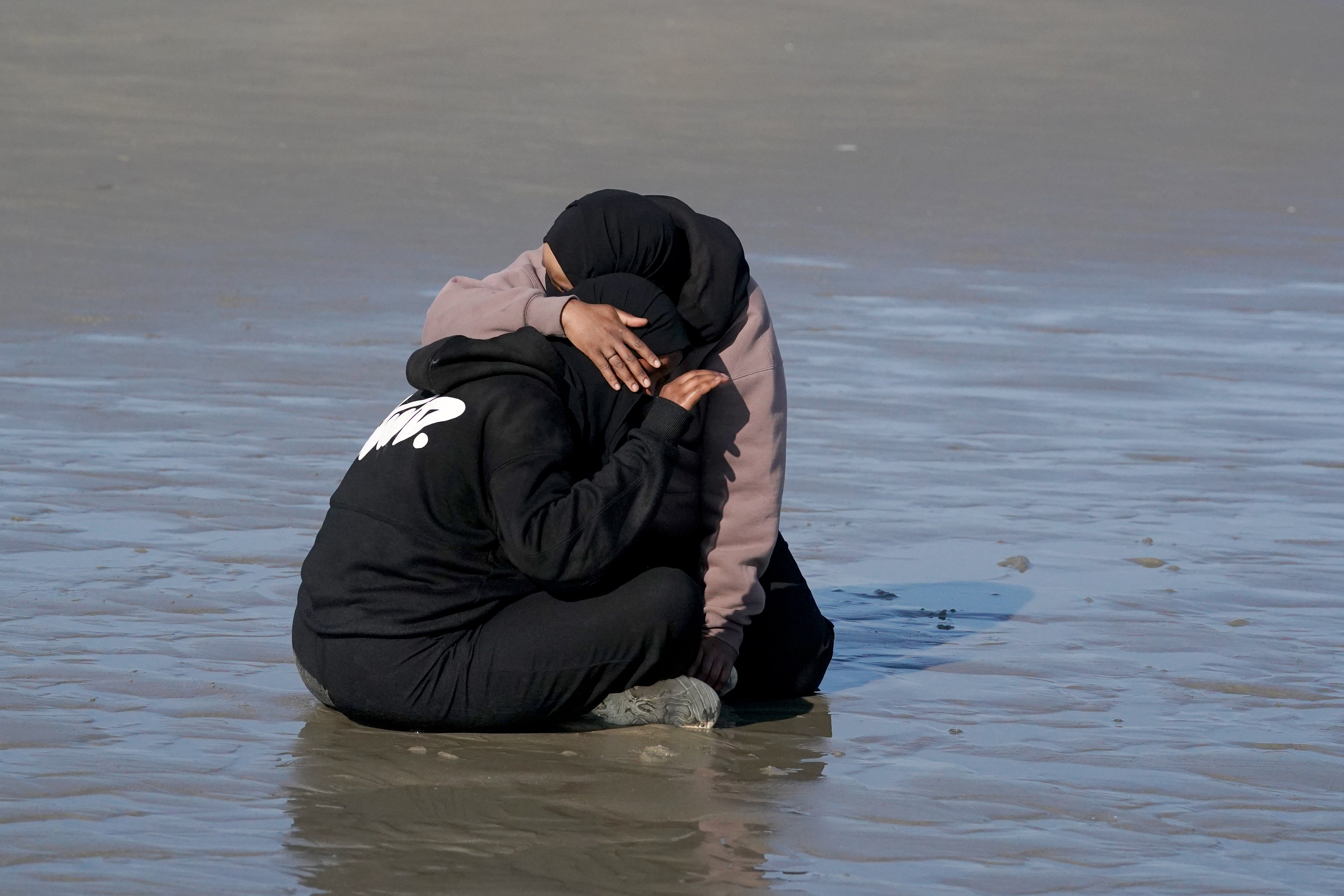 People thought to be migrants embrace on the beach at Gravelines, France, as they wait to board a small boat in an attempt to reach the UK by crossing the English Channel (Gareth Fuller/PA)
