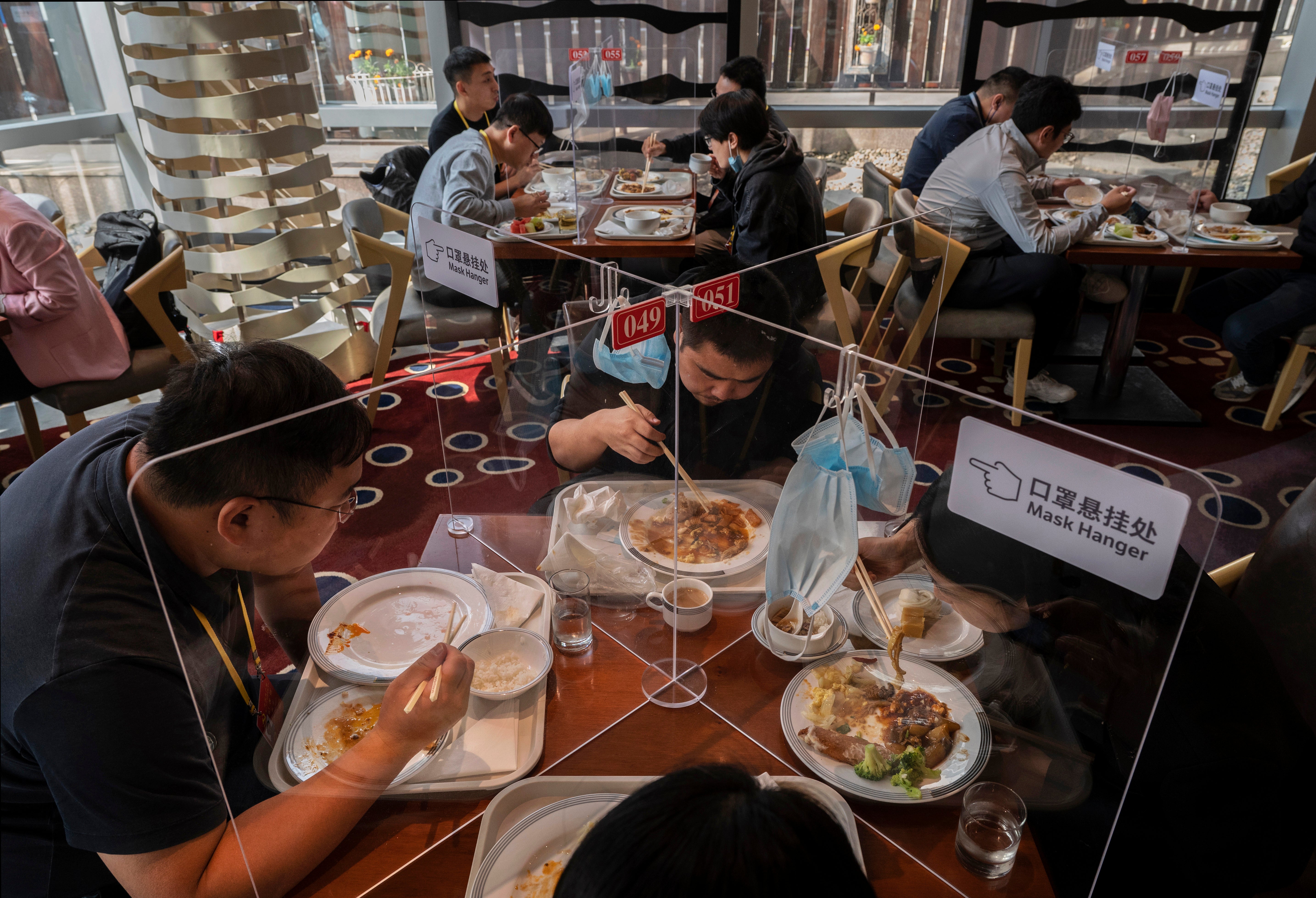 People eat behind plexiglass dividers at a restaurant for journalists and officials at the press centre for the 20th National Congress of the Communist Party of China during Covid times in 2022