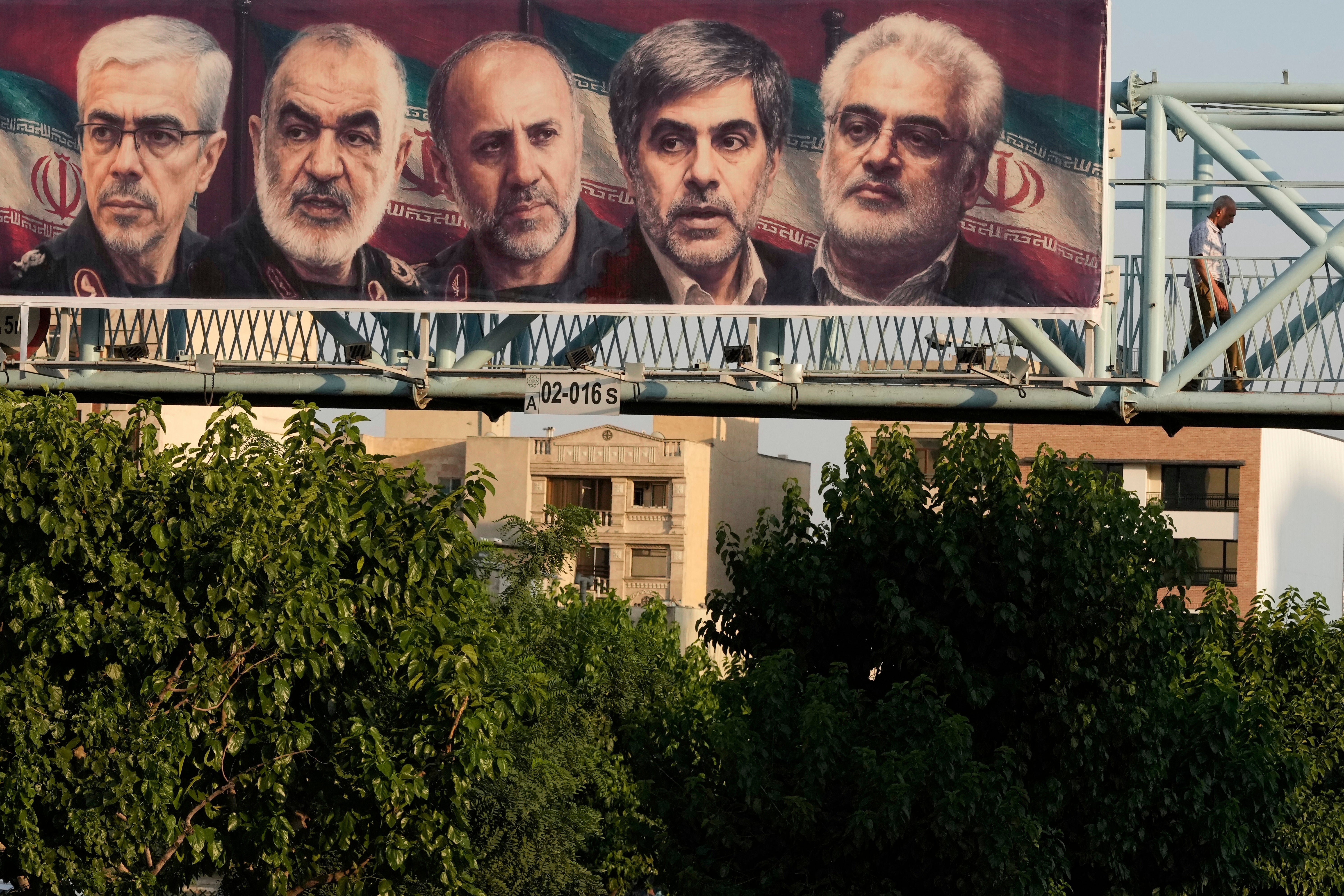 A man walks past a billboard displaying images of top Iranian commanders and scientists killed in Israeli strikes early Friday, in Tehran, Iran, Friday, June 13, 2025. (AP Photo/Vahid Salemi)