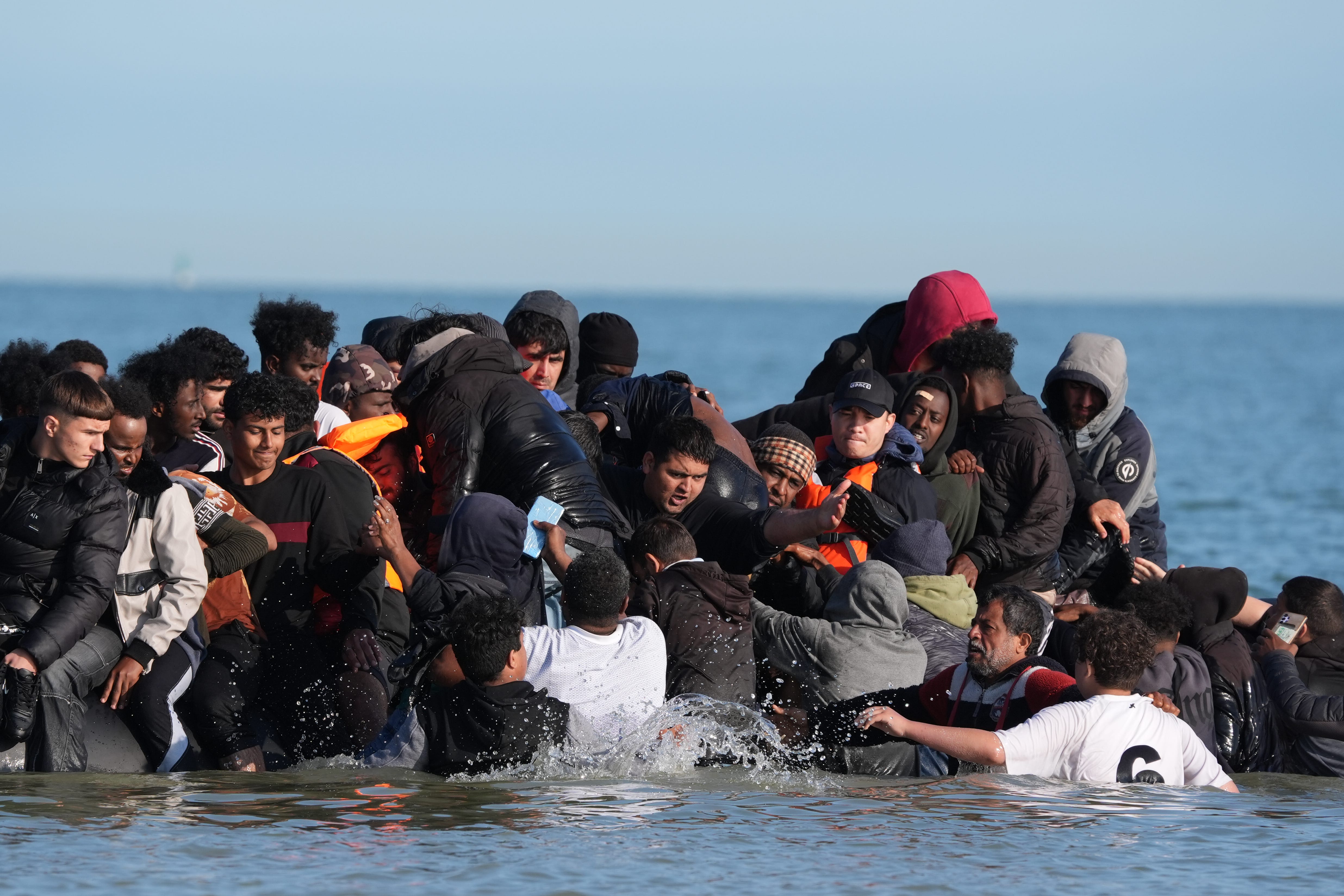 A group of people thought to be migrants board a dinghy near the beach at Gravelines, France (PA)