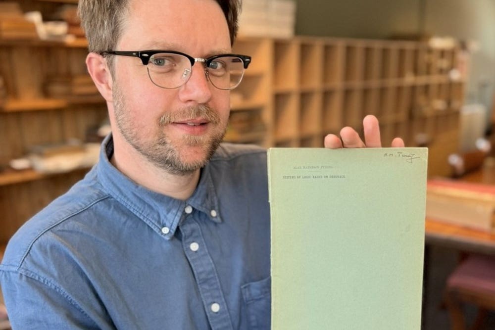 Rare Book Auctions director Jim Spencer holds Alan Turing’s PhD dissertation (Rare Book Auctions/PA)