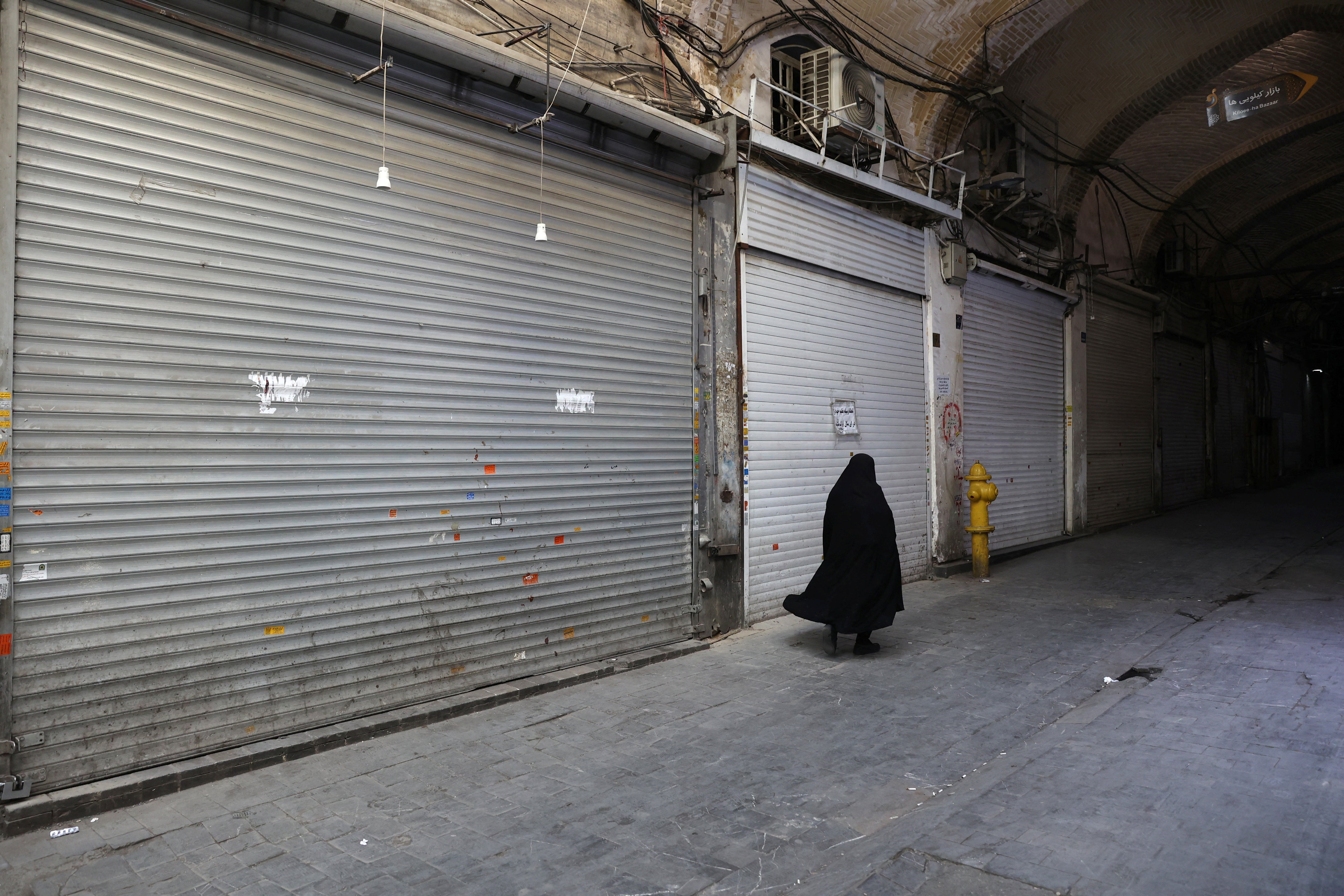 A person walks in front of closed shops in the Tehran Bazaar following the Israeli strikes on Iran