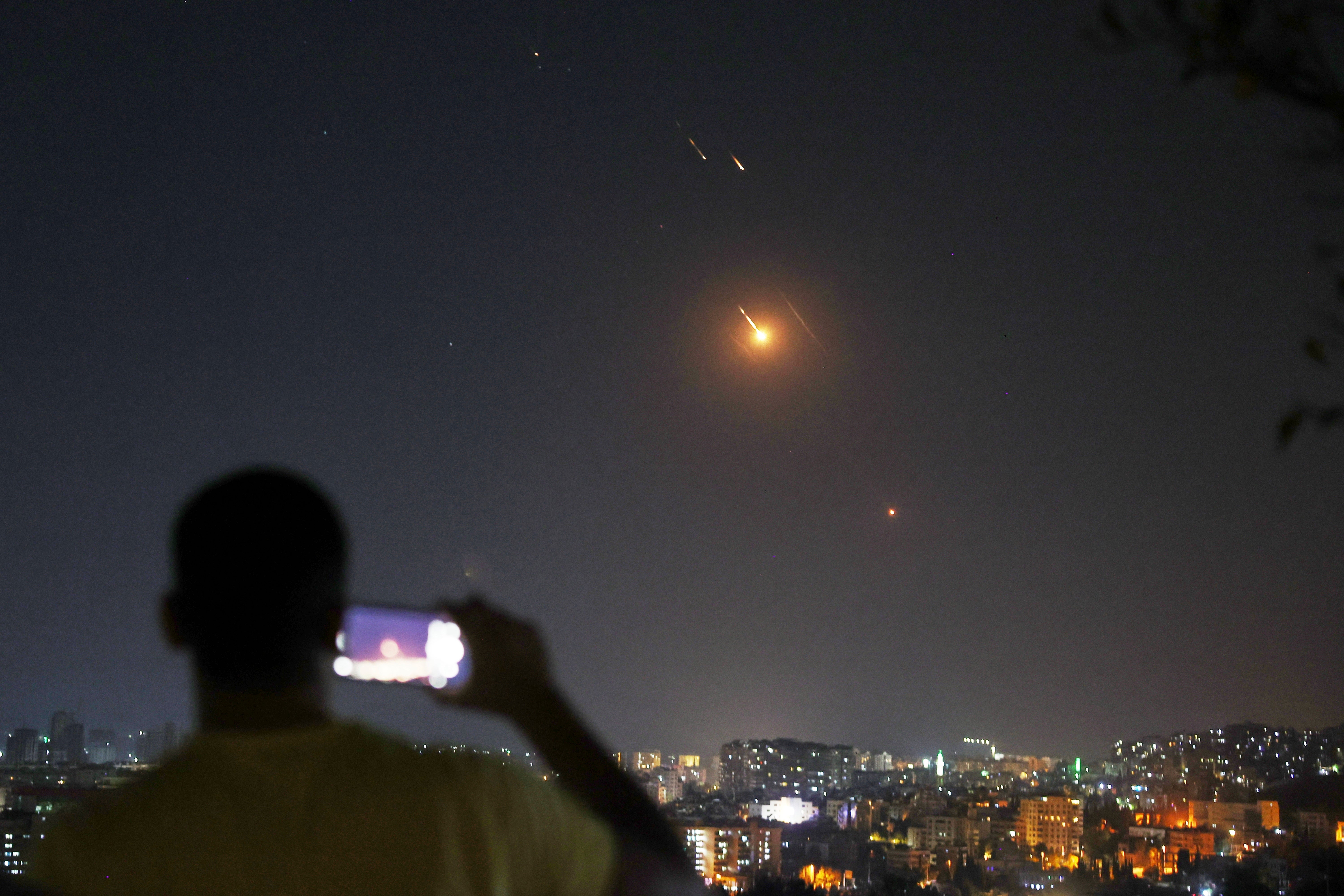 A man takes a photo as missiles fired from Iran towards Israel fly over Syrian territory in Damascus, Syria (Ghaith Alsayed via AP)