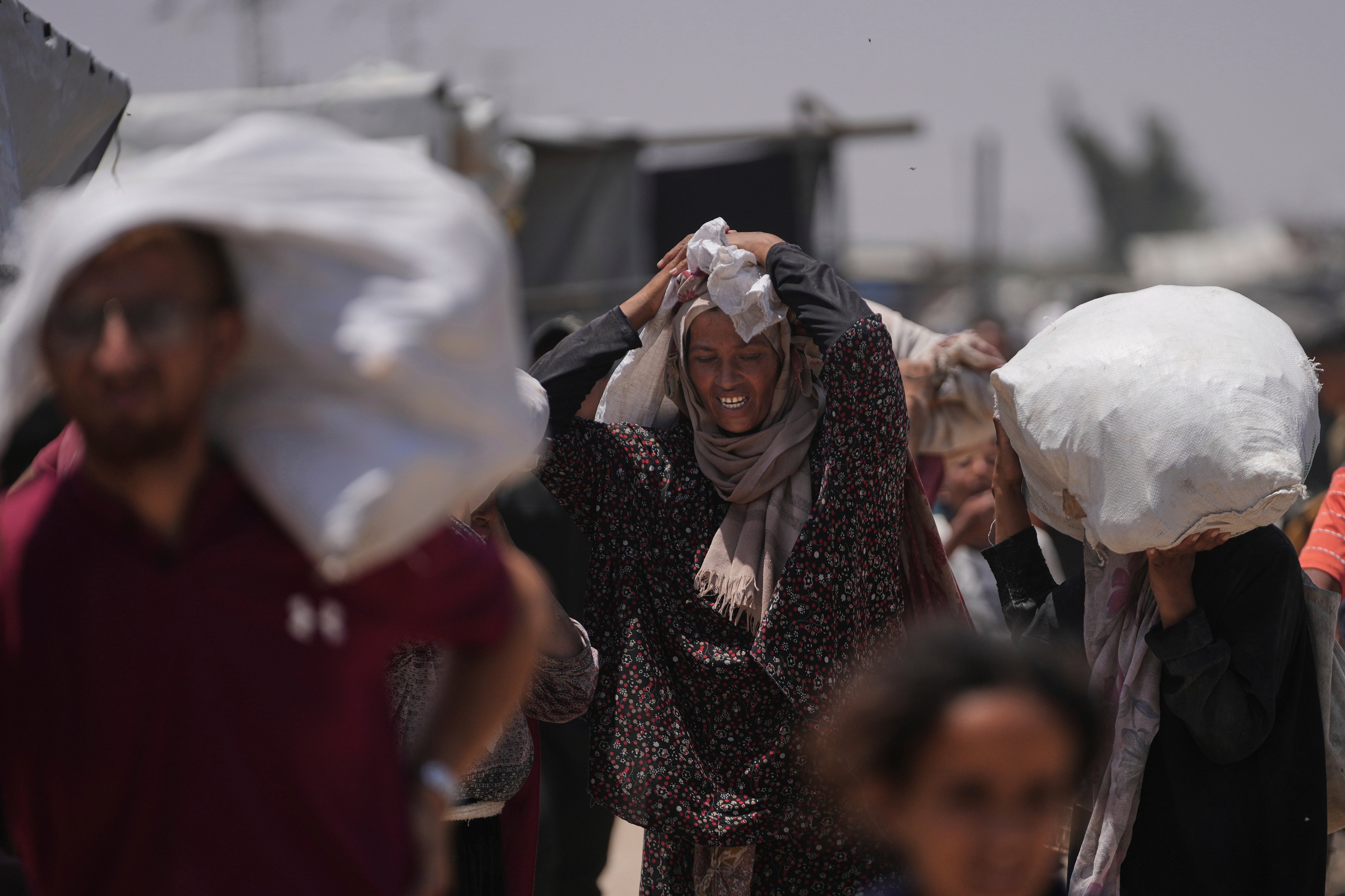 Palestinians carry bags containing food and humanitarian aid packages delivered by the Gaza Humanitarian Foundation, a U.S.-backed organization, in Rafah, southern Gaza Strip, Monday, June 16, 2025.