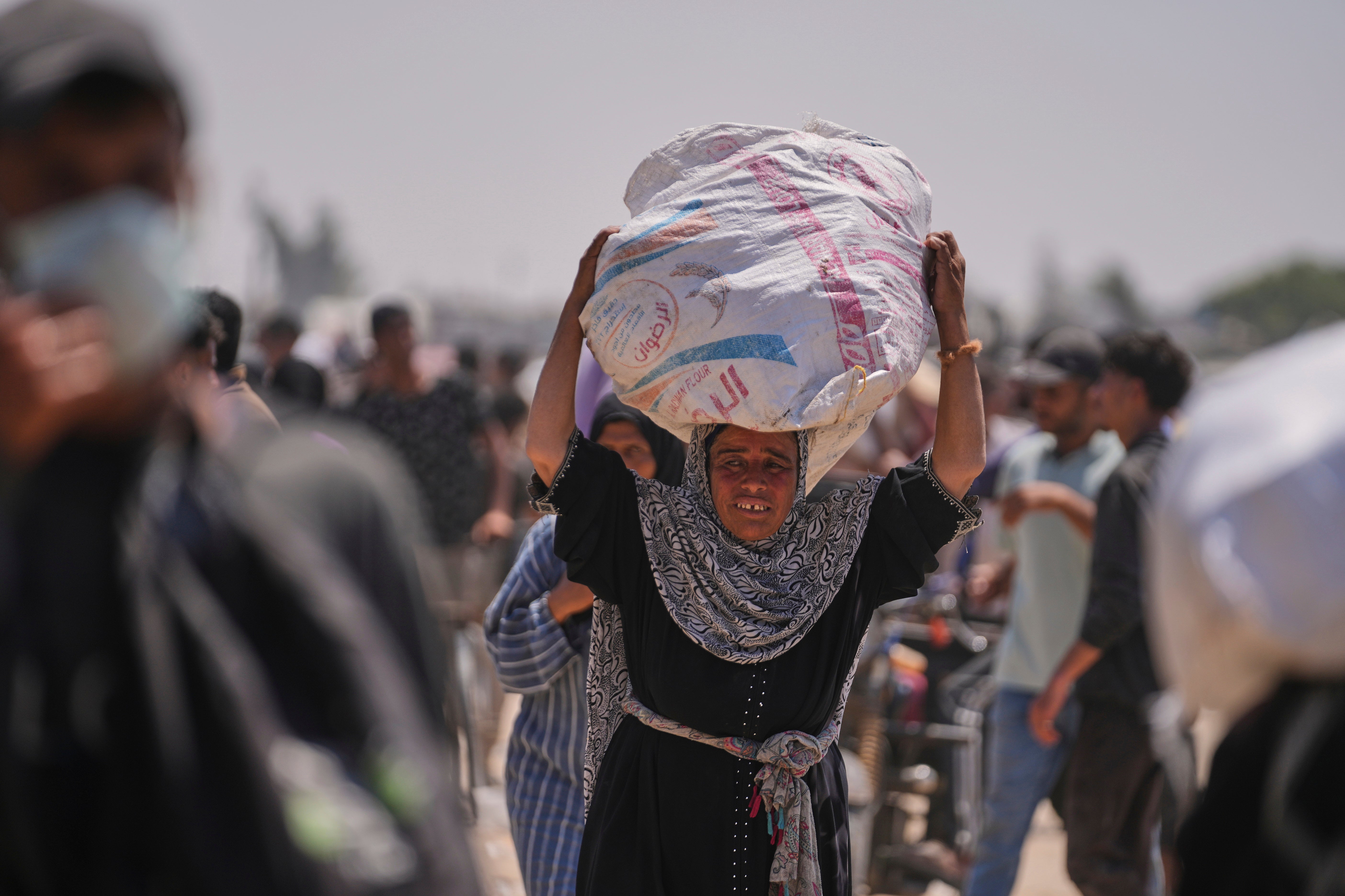 A Palestinian woman carries a bag containing food and humanitarian aid delivered by the Gaza Humanitarian Foundation in Rafah