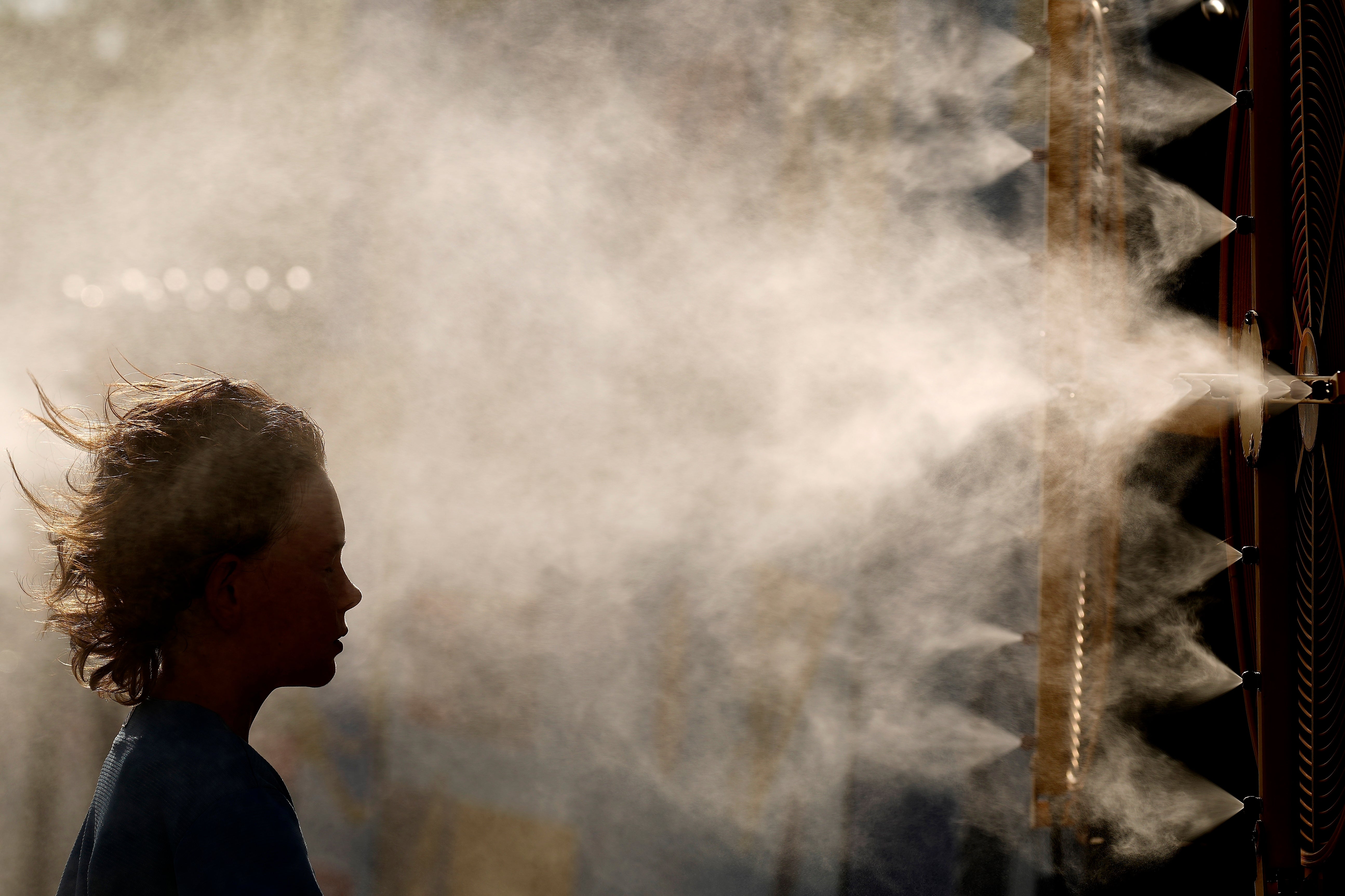Michael Mullenax, 10, from Lee's Summit, Mo., cools off in a mister at Kauffman Stadium before a baseball game between the Kansas City Royals and the Miami Marlins, June 24, 2024, in Kansas City, Mo